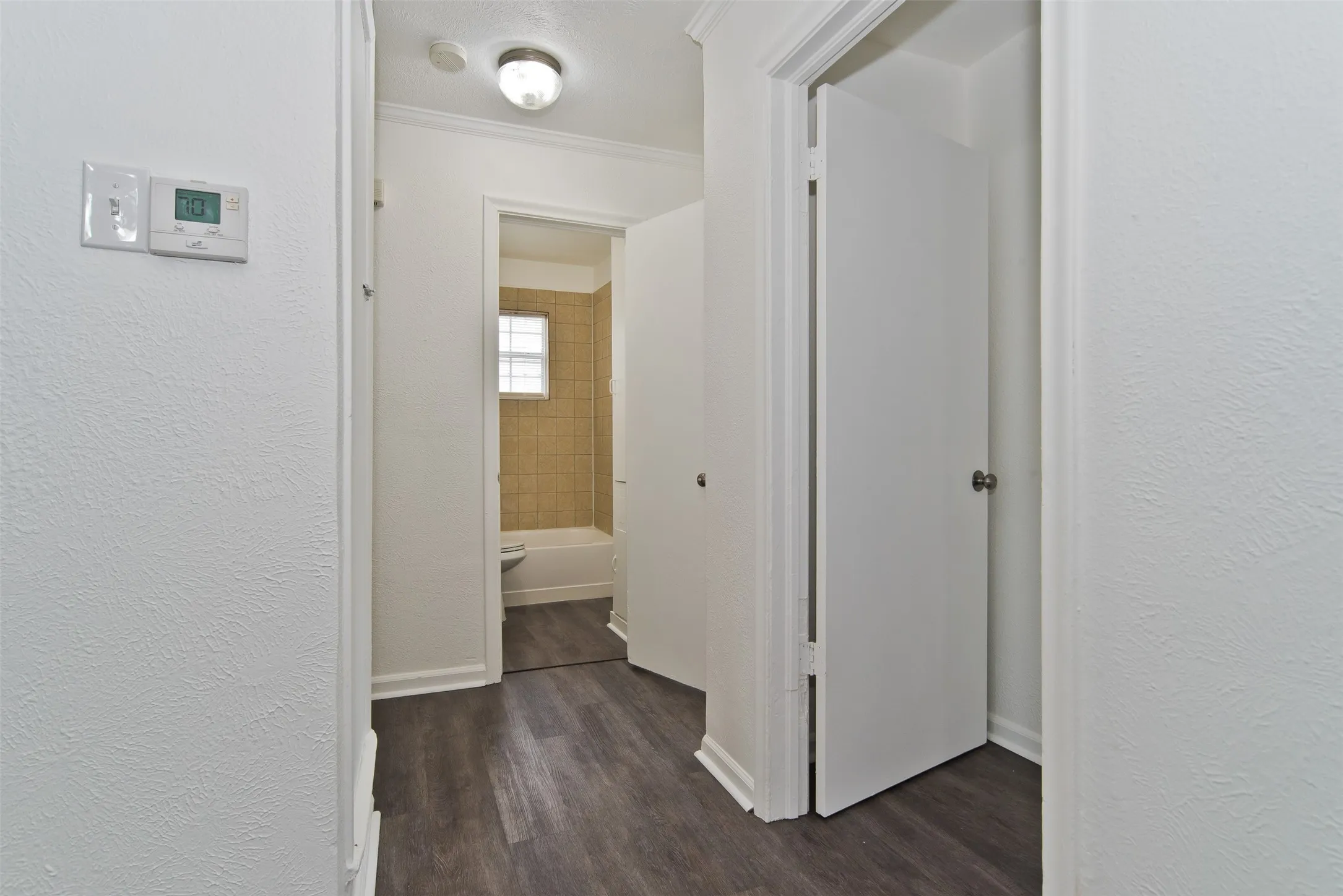 Hallway featuring wood-finish flooring, white trim, and a flush-mount ceiling light