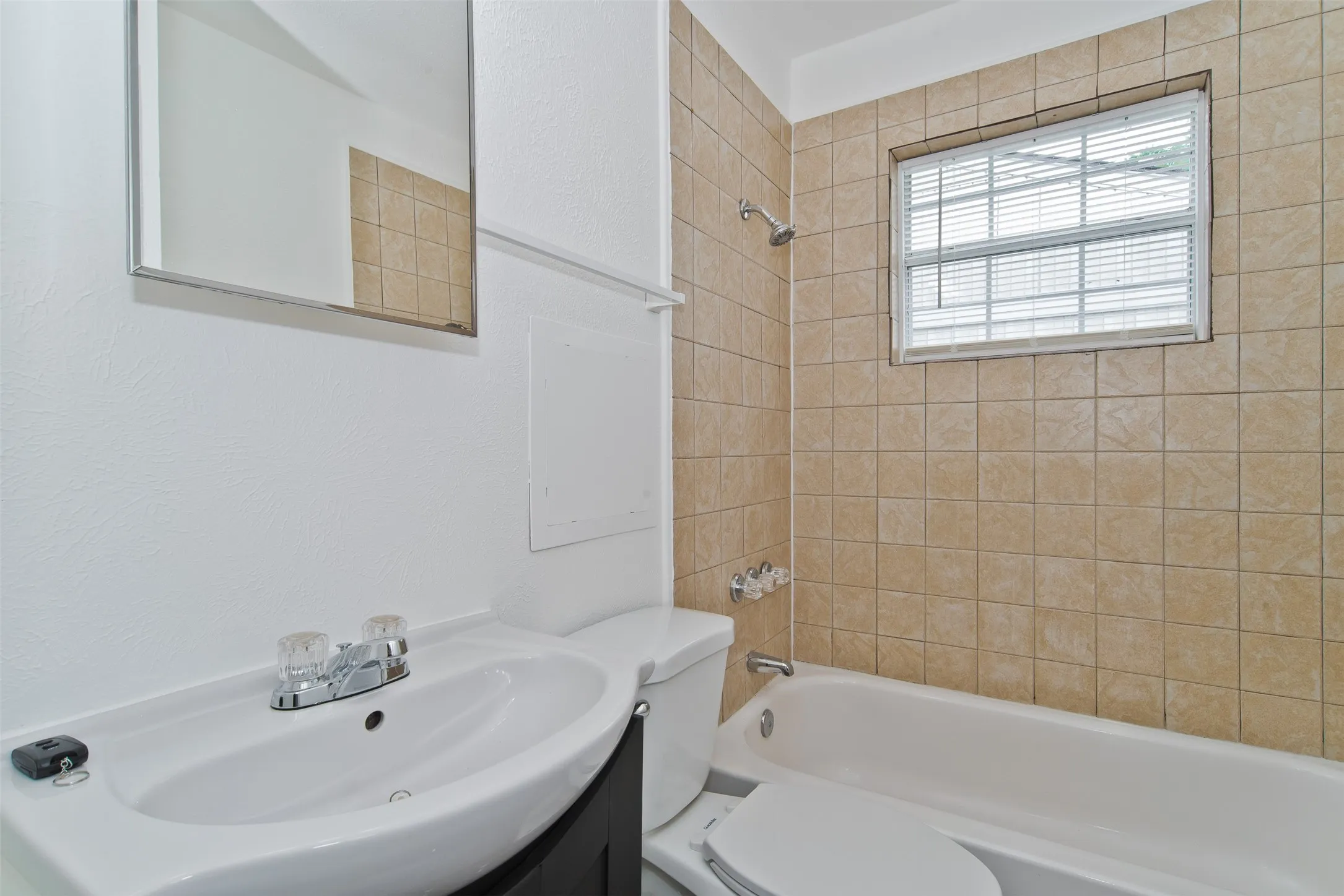Bathroom featuring a white vanity sink with a chrome faucet, a rectangular mirror, and a white toilet
