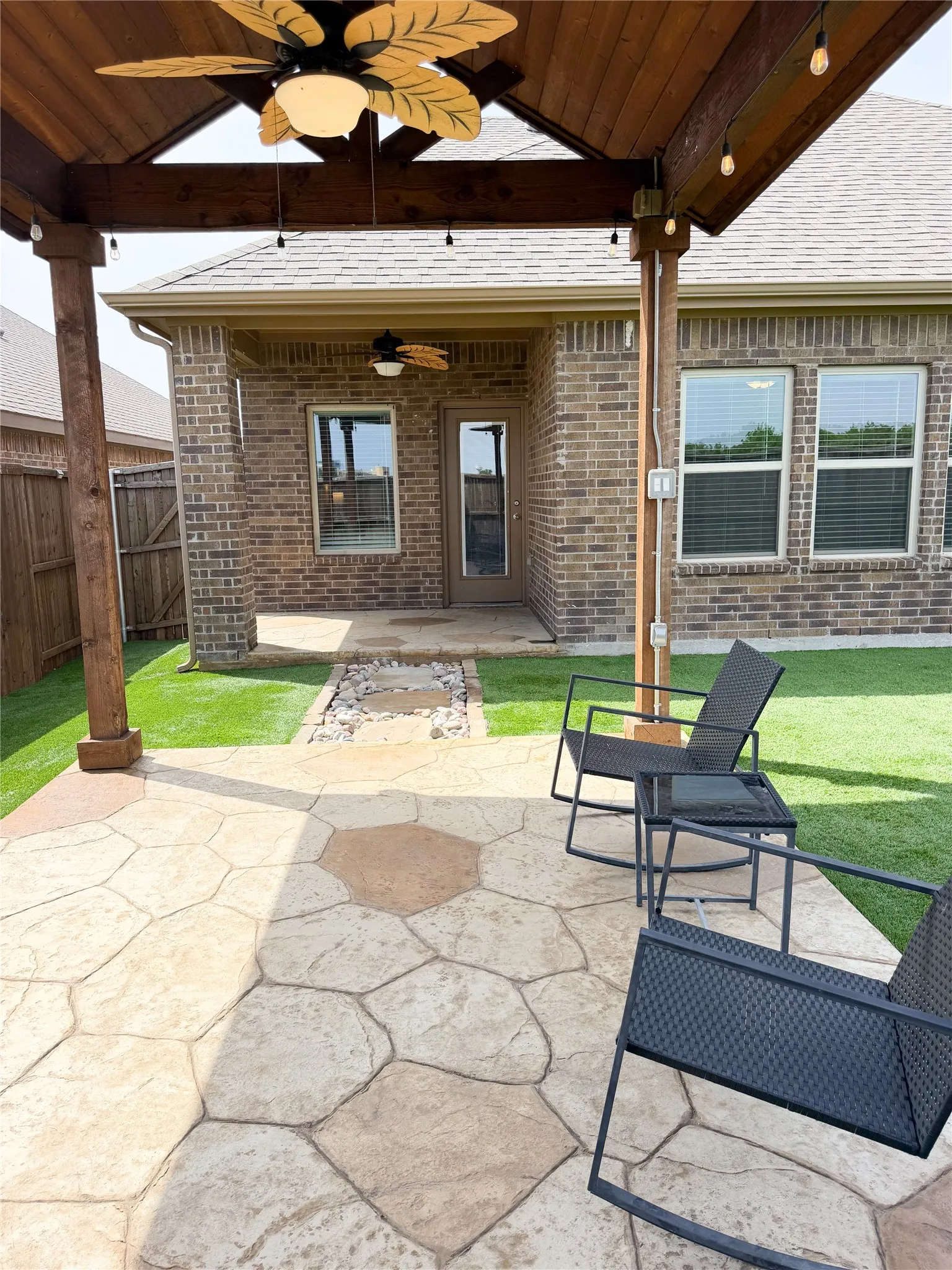 Step Outside to Enjoy Outdoor Living Space Flagstone and Rock Pathway Lead to 13 x 11 Artfully Crafted Pergola with a Solid Gabled Roof, Matching Integrated Ceiling Fans Patio and Pergola, Bistro Lighting and Flagstone Inspired Stained Concrete. The Perfect Boutique Space for Year-Round Chilling.