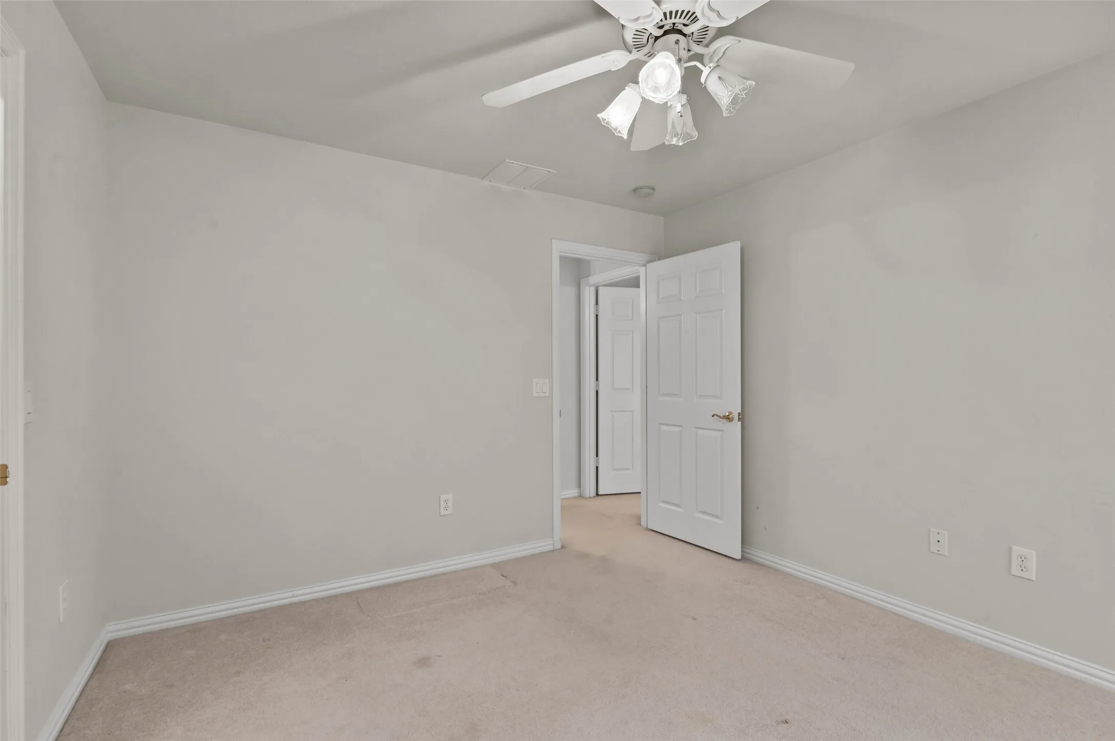 Upstairs bedroom with carpeted flooring and ceiling fan.  The bedroom has a door out to the large covered balcony overlooking the golf course.