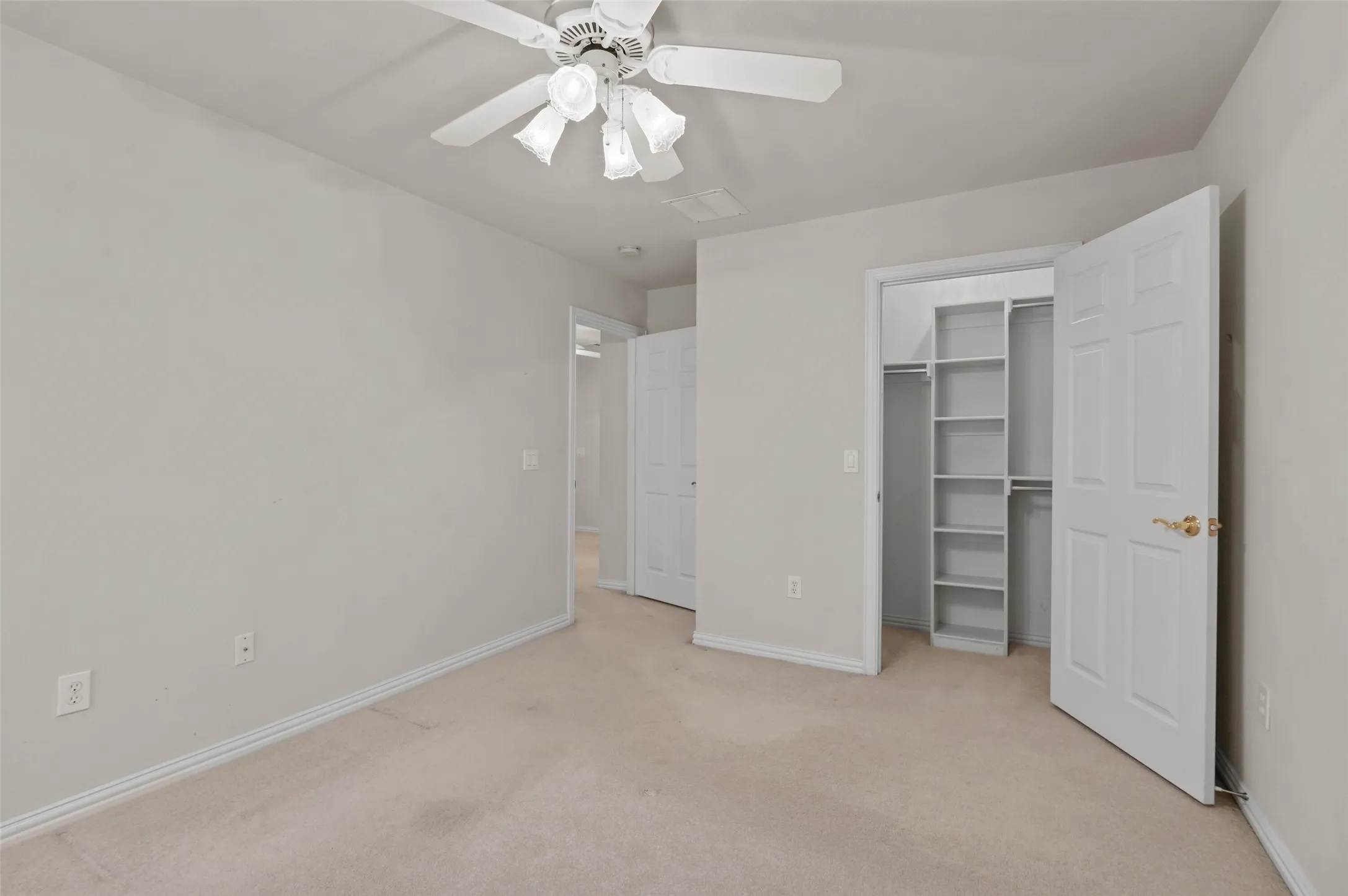 Upstairs bedroom with carpeted flooring and ceiling fan.  The bedroom has a door out to the large covered balcony overlooking the golf course.
