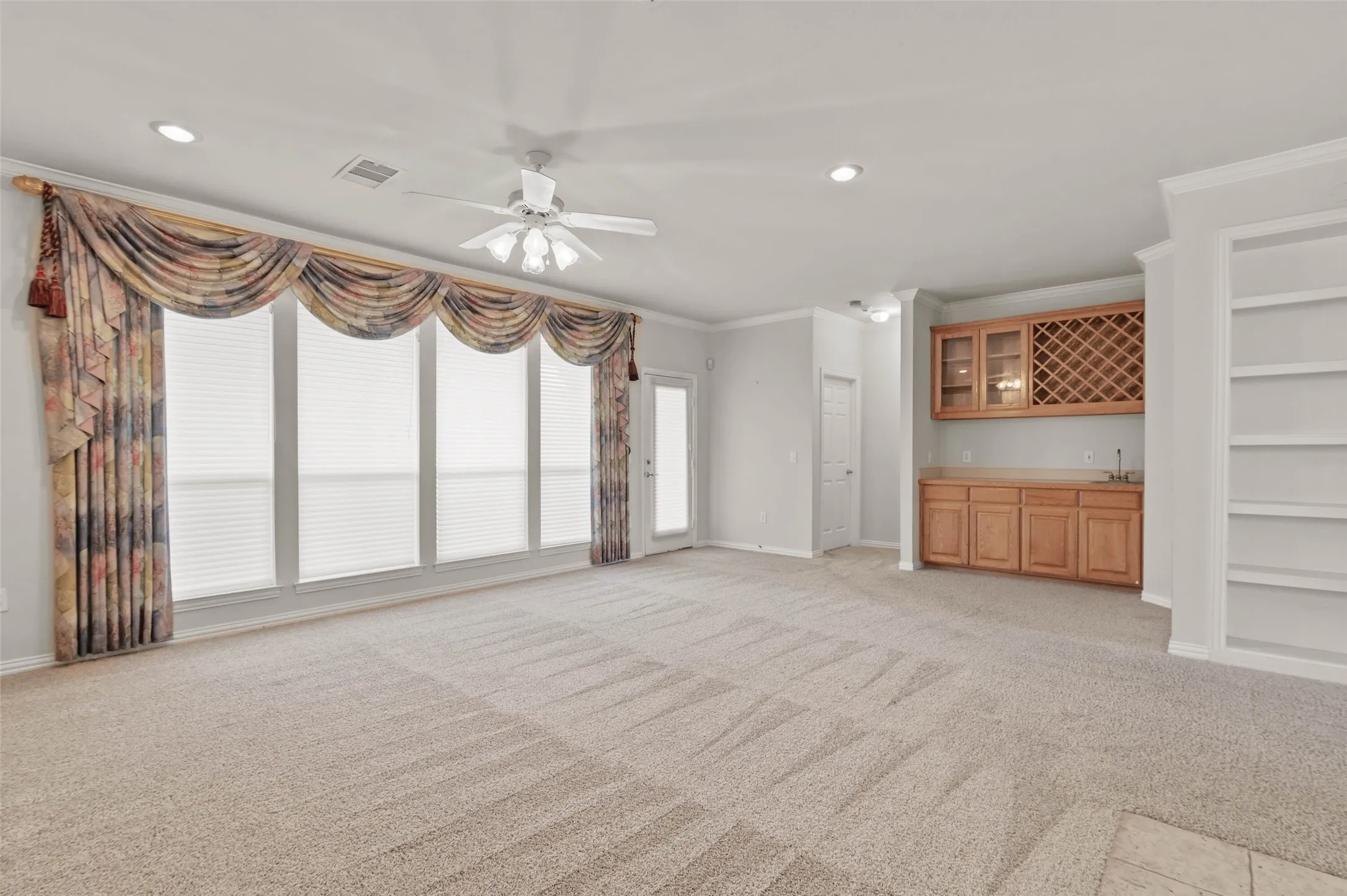 View of the huge living room with large windows overlooking the golf course and a wet bar.