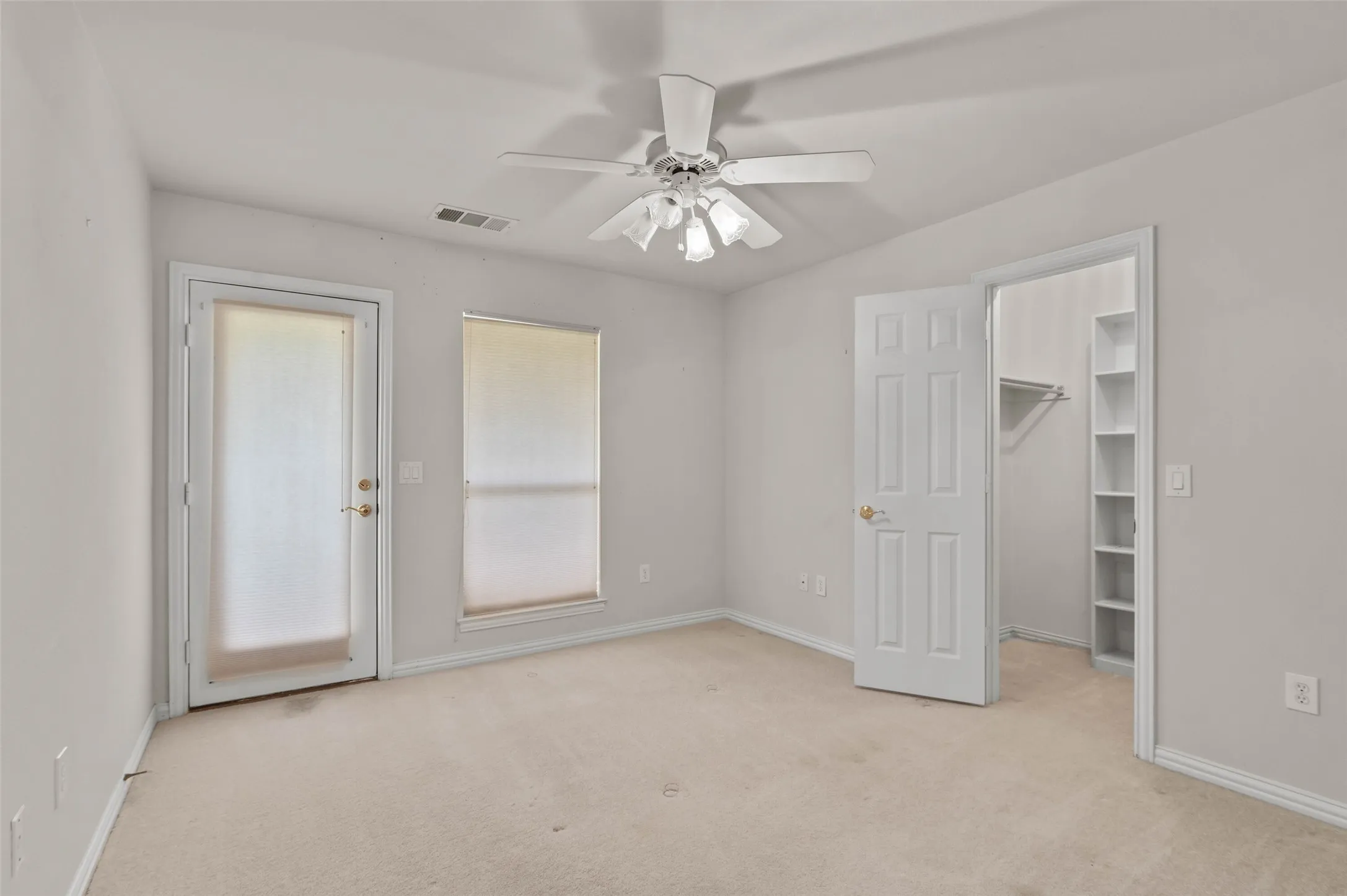 Upstairs bedroom with carpeted flooring and ceiling fan.  The bedroom has a door out to the large covered balcony overlooking the golf course.