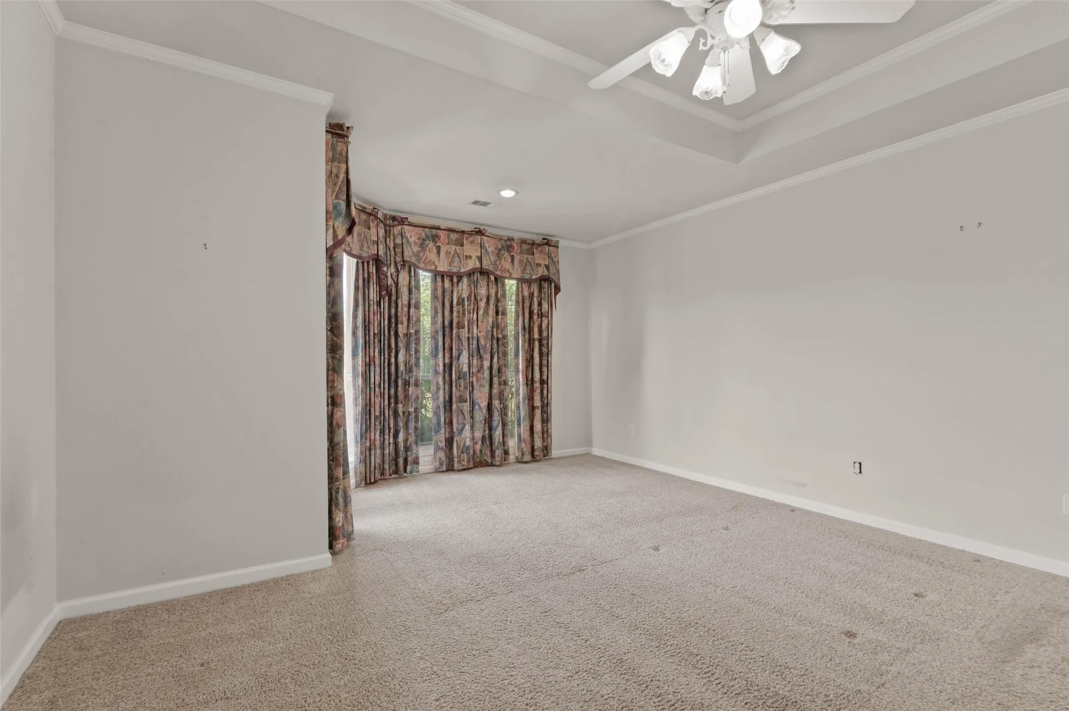 Huge primary bedroom with carpeted flooring, ceiling fan and huge windows looking out onto the golf course.