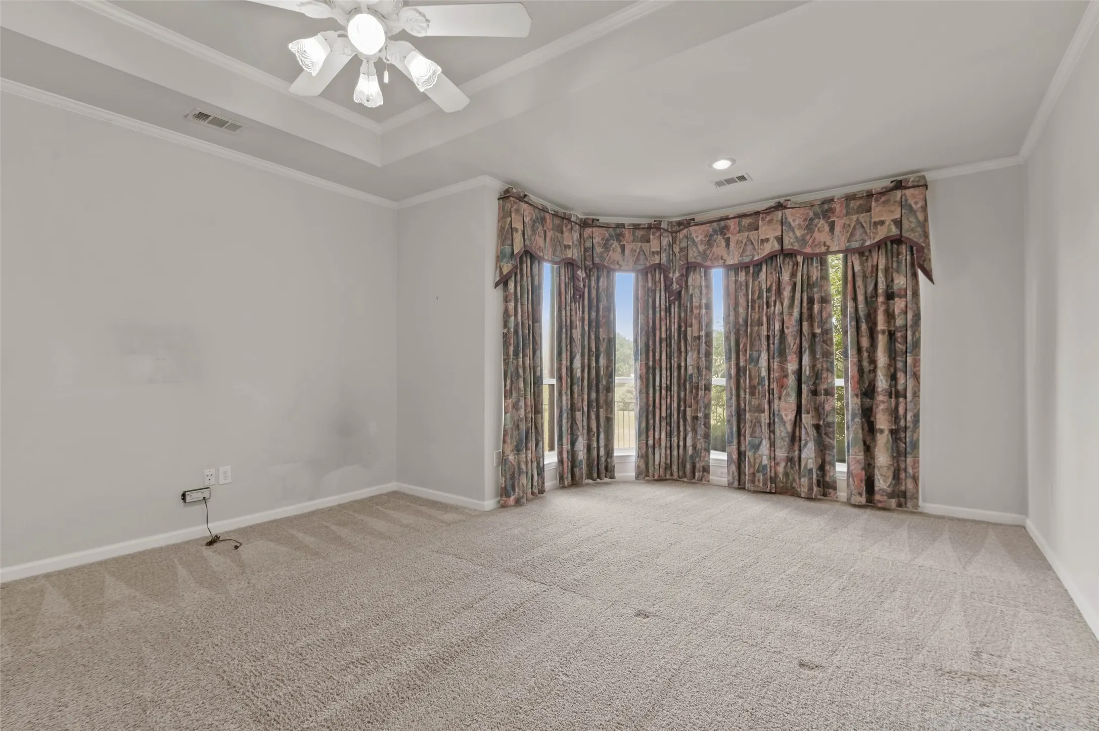 Huge primary bedroom with carpeted flooring, ceiling fan and huge windows looking out onto the golf course.