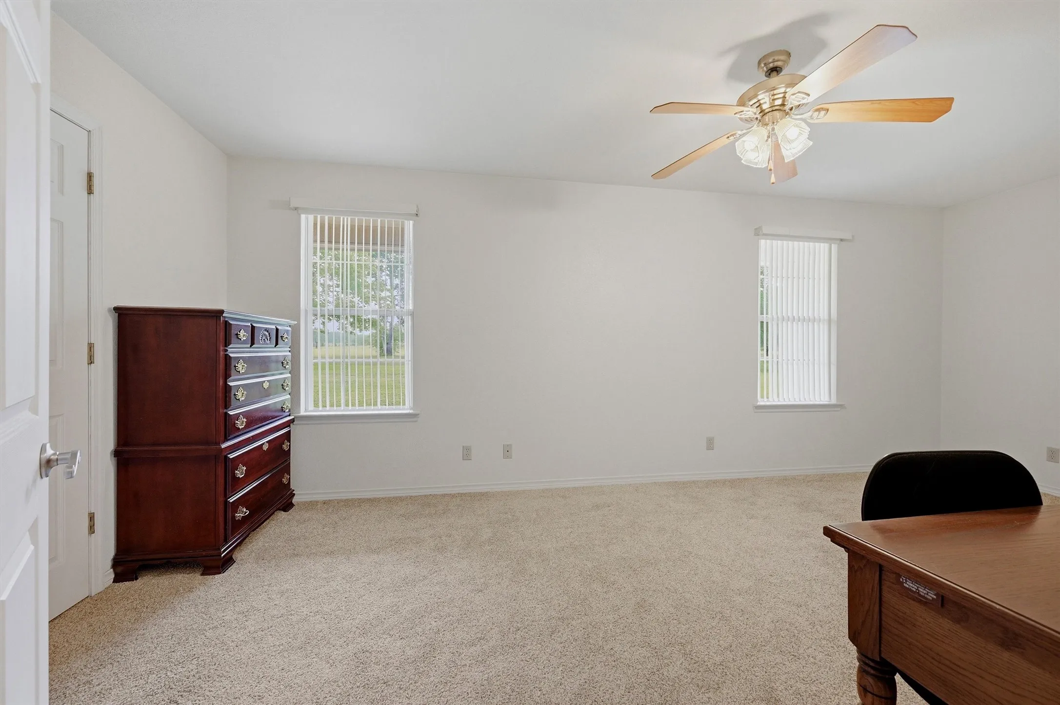 Spacious interior featuring a neutral carpeted floor, white walls, and two windows with vertical blinds