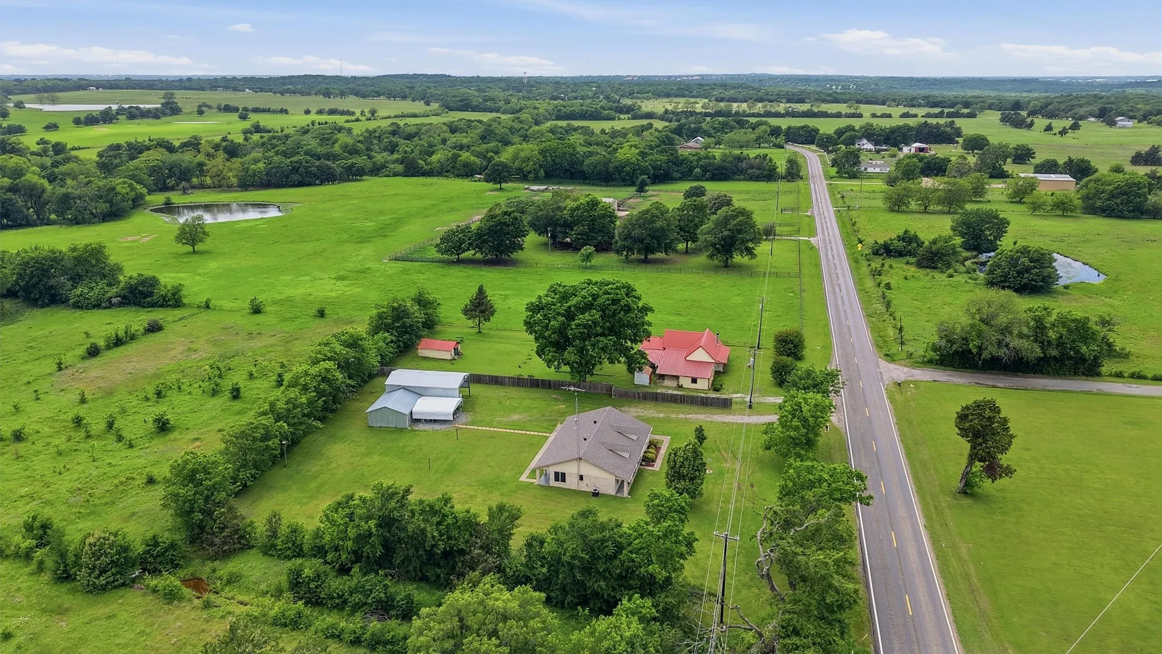 Expansive rural property featuring two residential structures, multiple outbuildings, and a pond