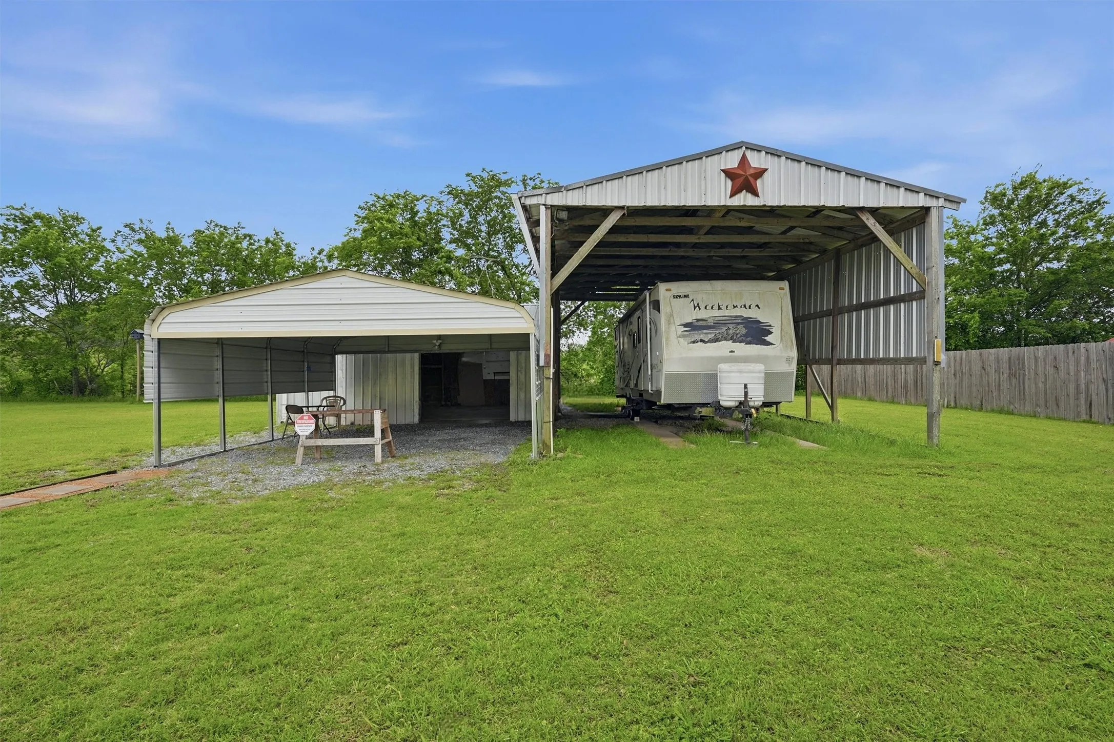 Gravel-covered RV parking structure with a metal roof and exposed wood beams