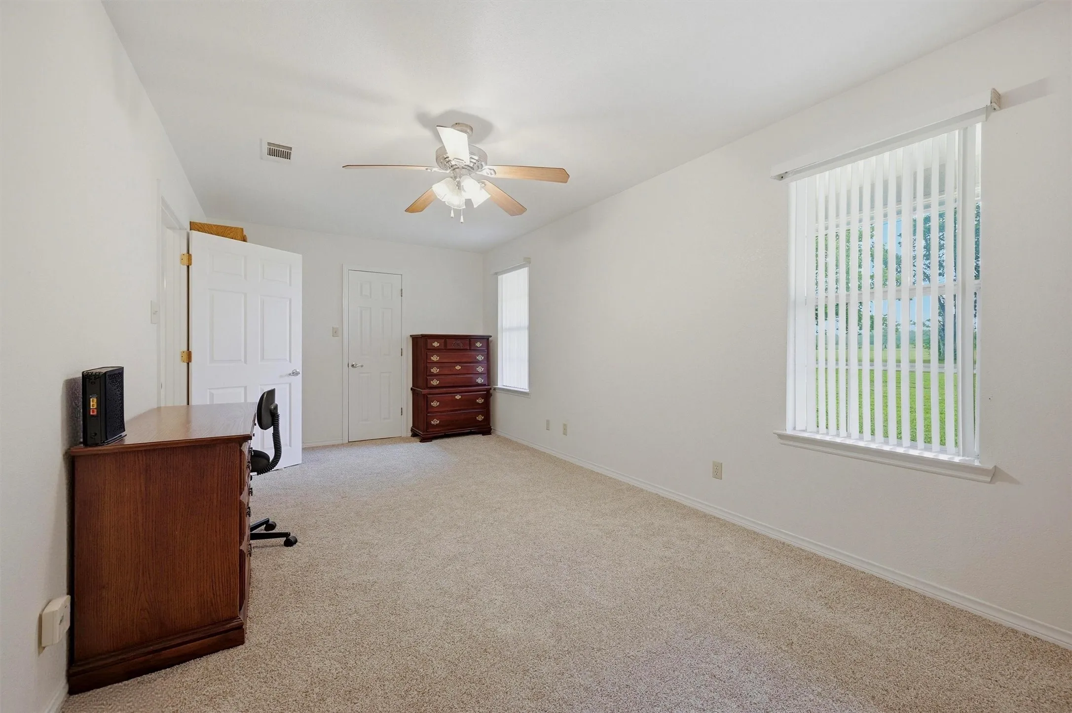 Neutral tone wall finishes, light-toned carpet, and a ceiling fan with light fixture