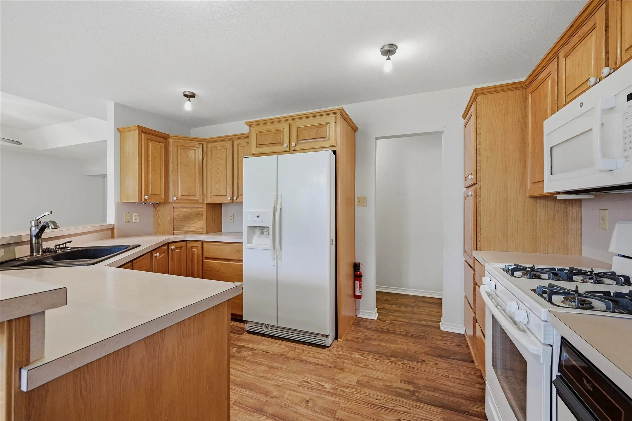 Kitchen featuring wood-finish flooring, light wood cabinetry, and neutral countertops