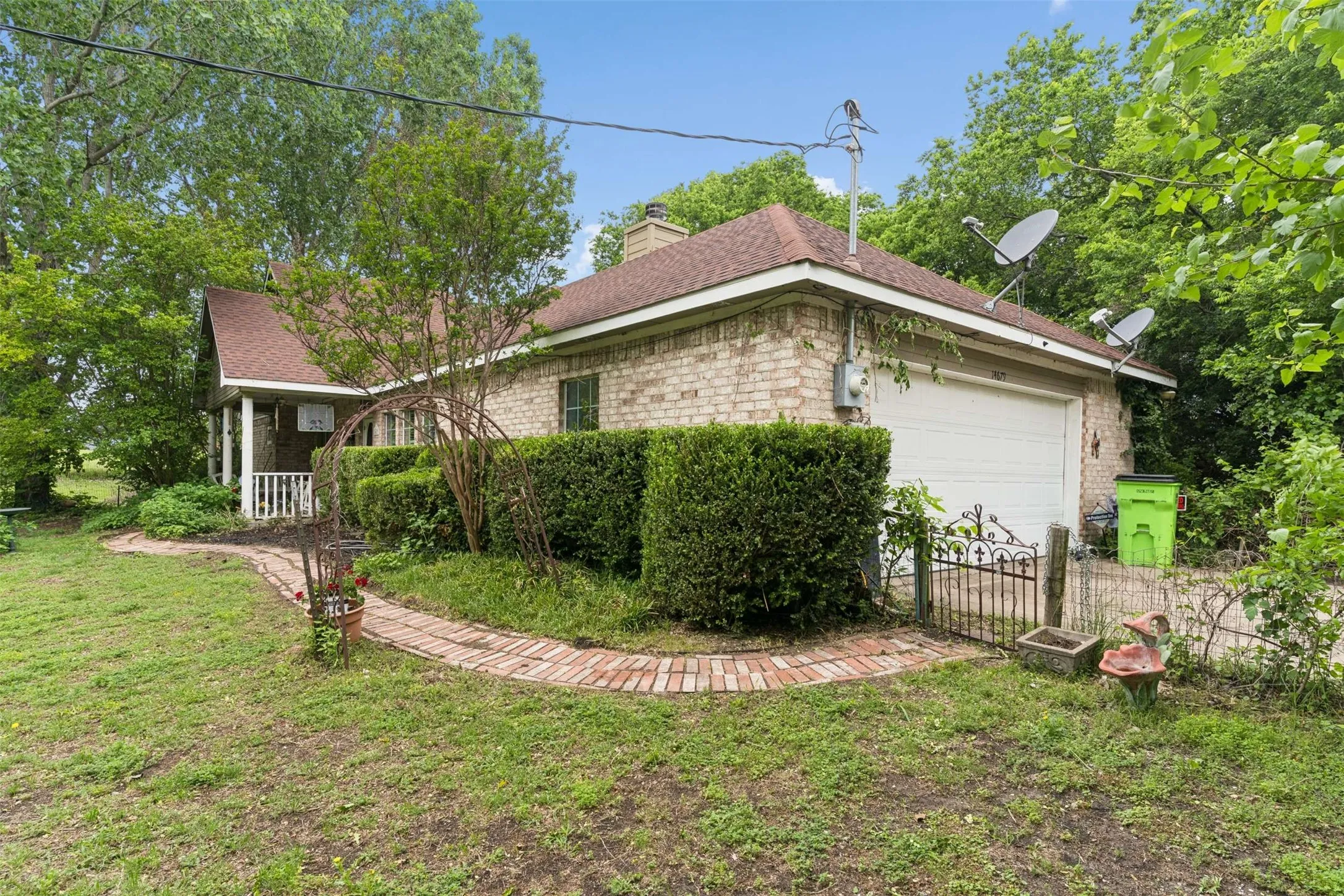 Brick exterior with a peaked roofline, an attached garage, and a covered front porch featuring white railing