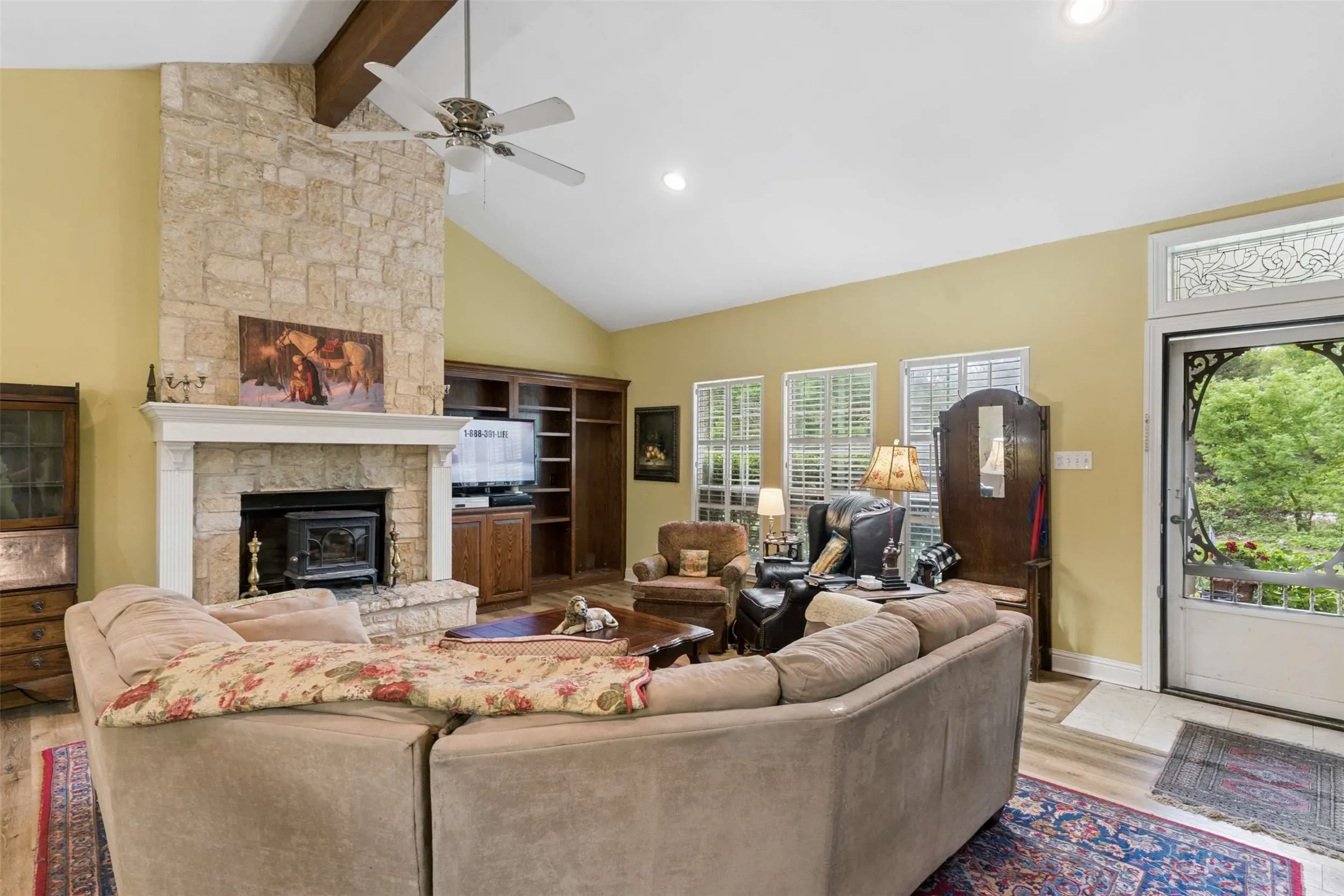 Spacious living area featuring a stone-clad fireplace with a wood-burning insert and a substantial mantel