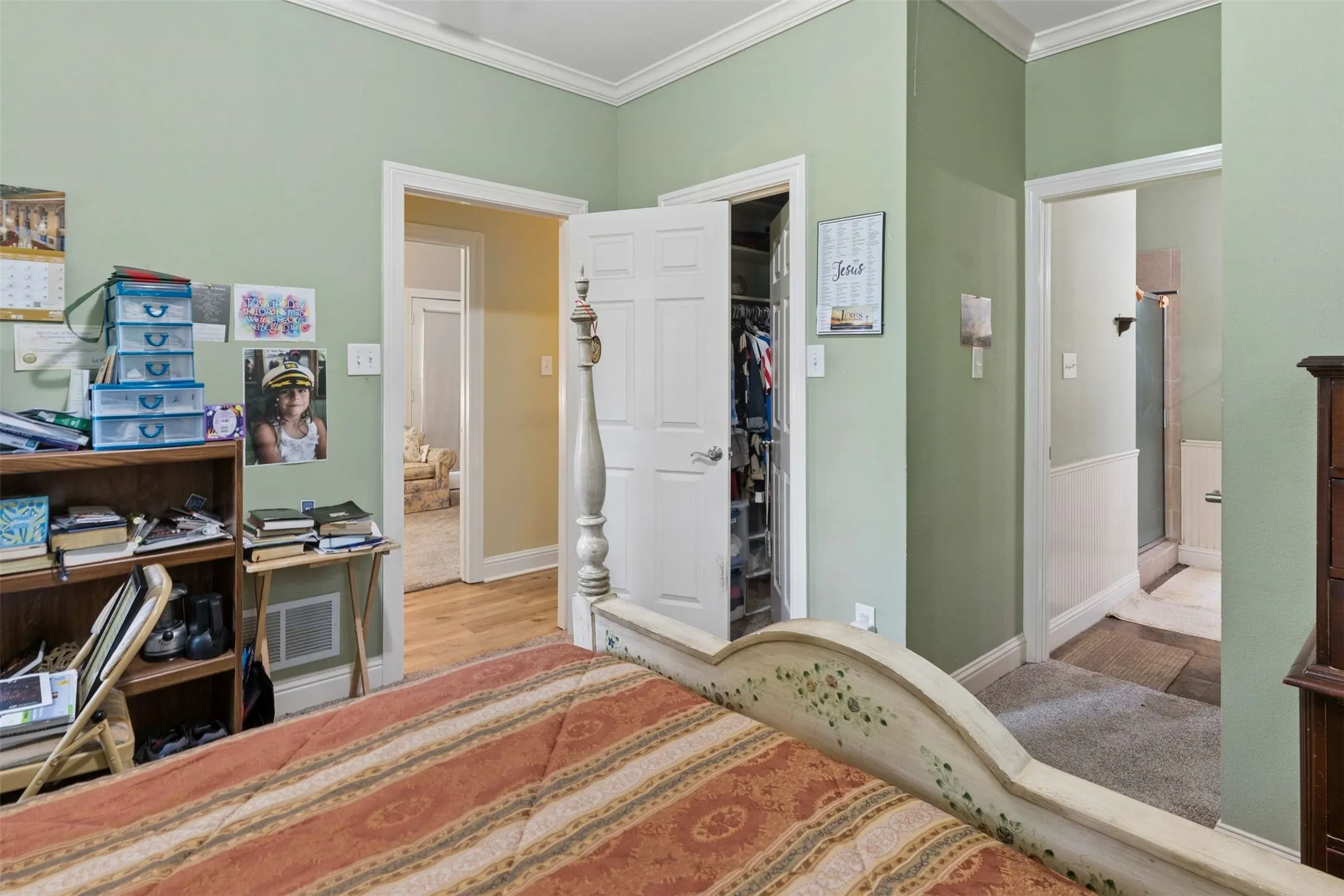 Bedroom featuring light green walls, crown molding, and a built-in closet with a paneled door
