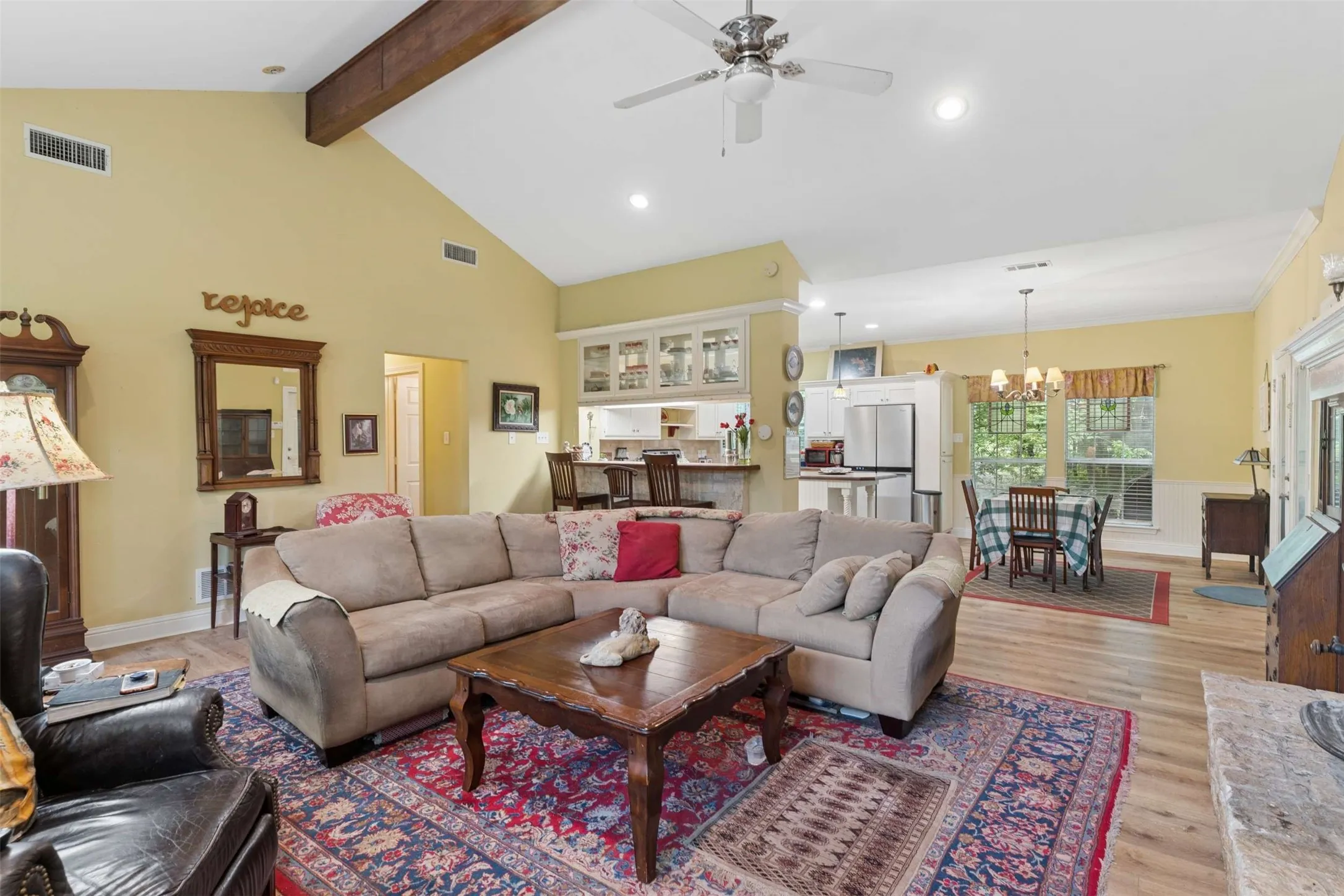 Spacious living area featuring a vaulted ceiling with exposed wood beams, wood-finish flooring, recessed lighting, and a ceiling fan