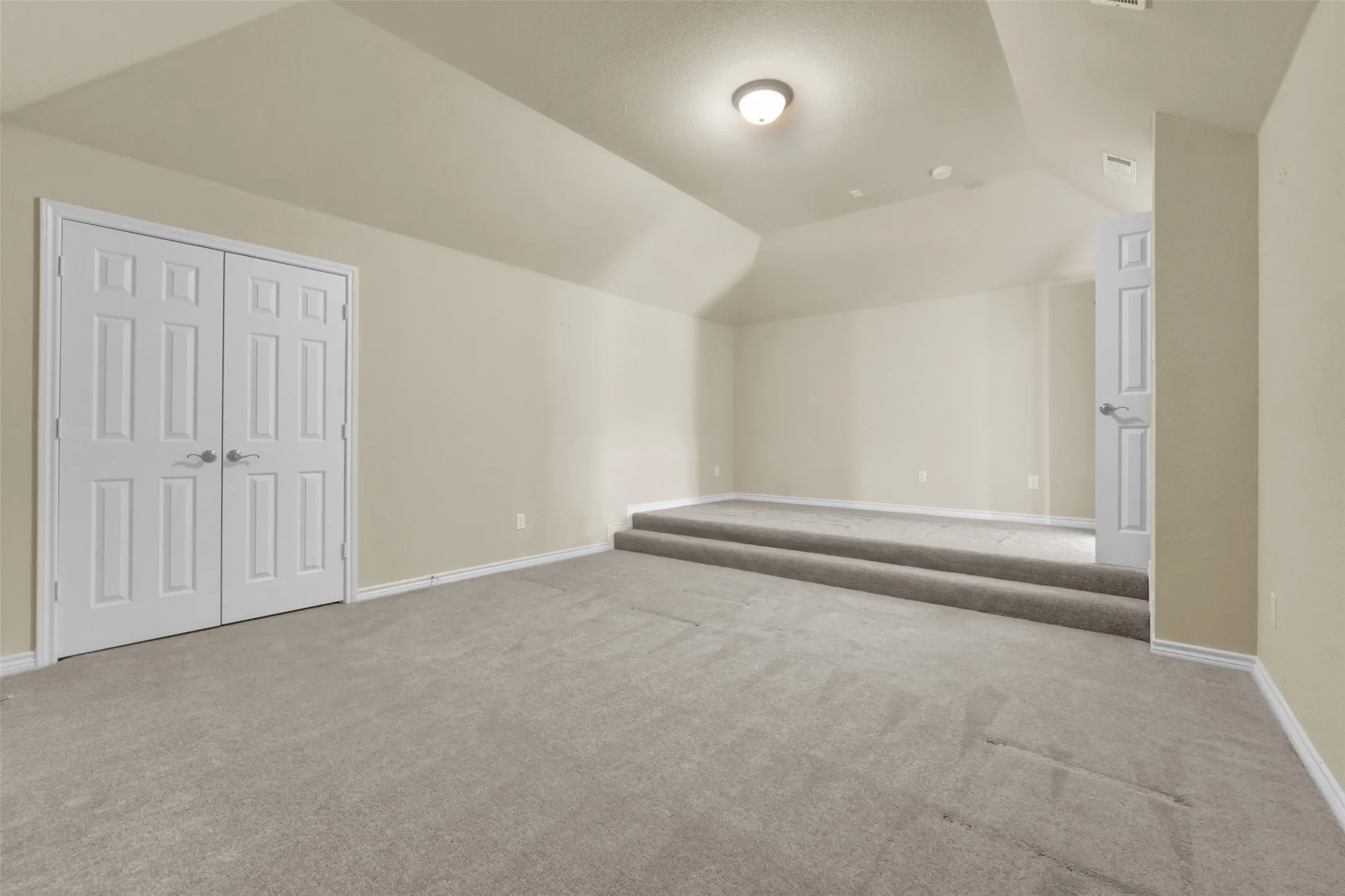 Carpeted room featuring a raised platform, recessed ceiling, neutral wall paint, and white trim