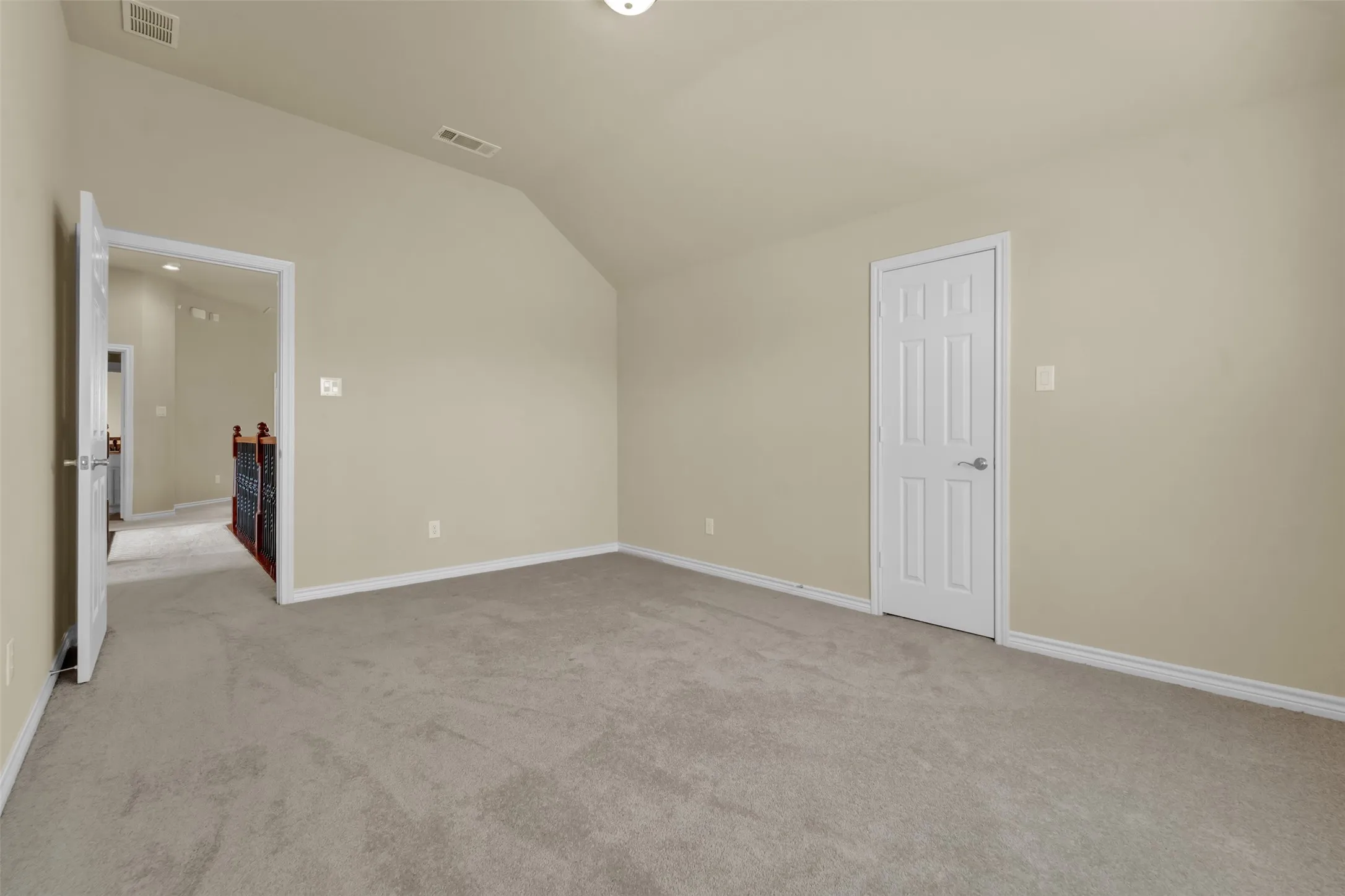 Room featuring vaulted ceiling, neutral wall tones, light gray carpeting, white baseboards, and a white six-panel door