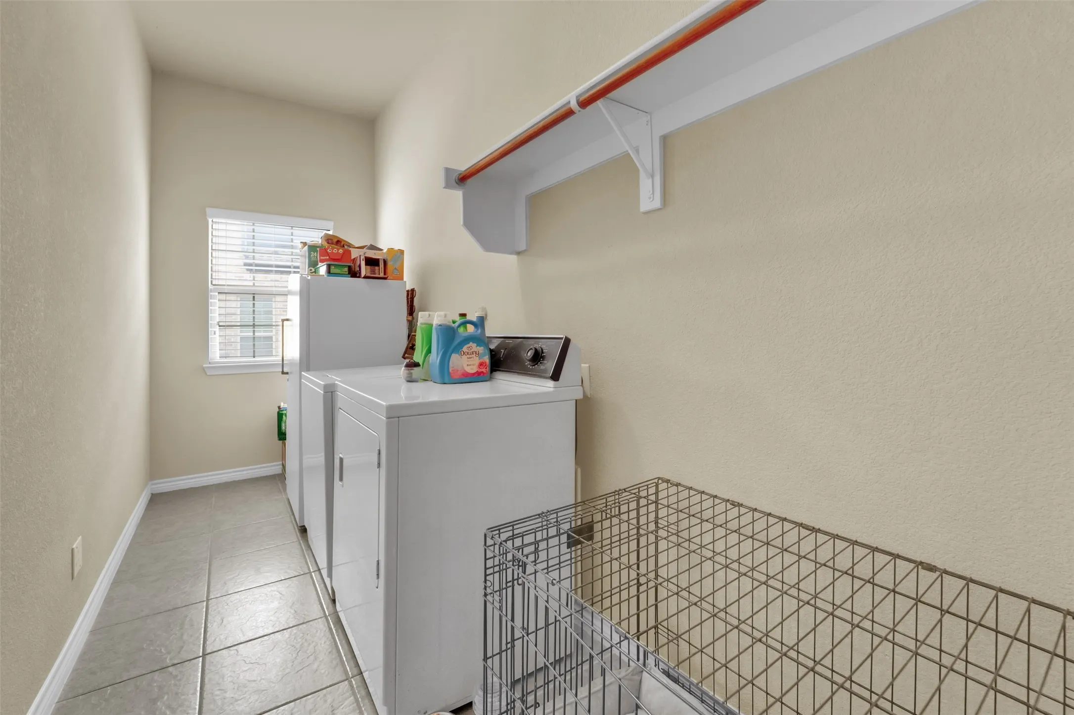 Utility room featuring light-toned walls, tile flooring, and a window with blinds