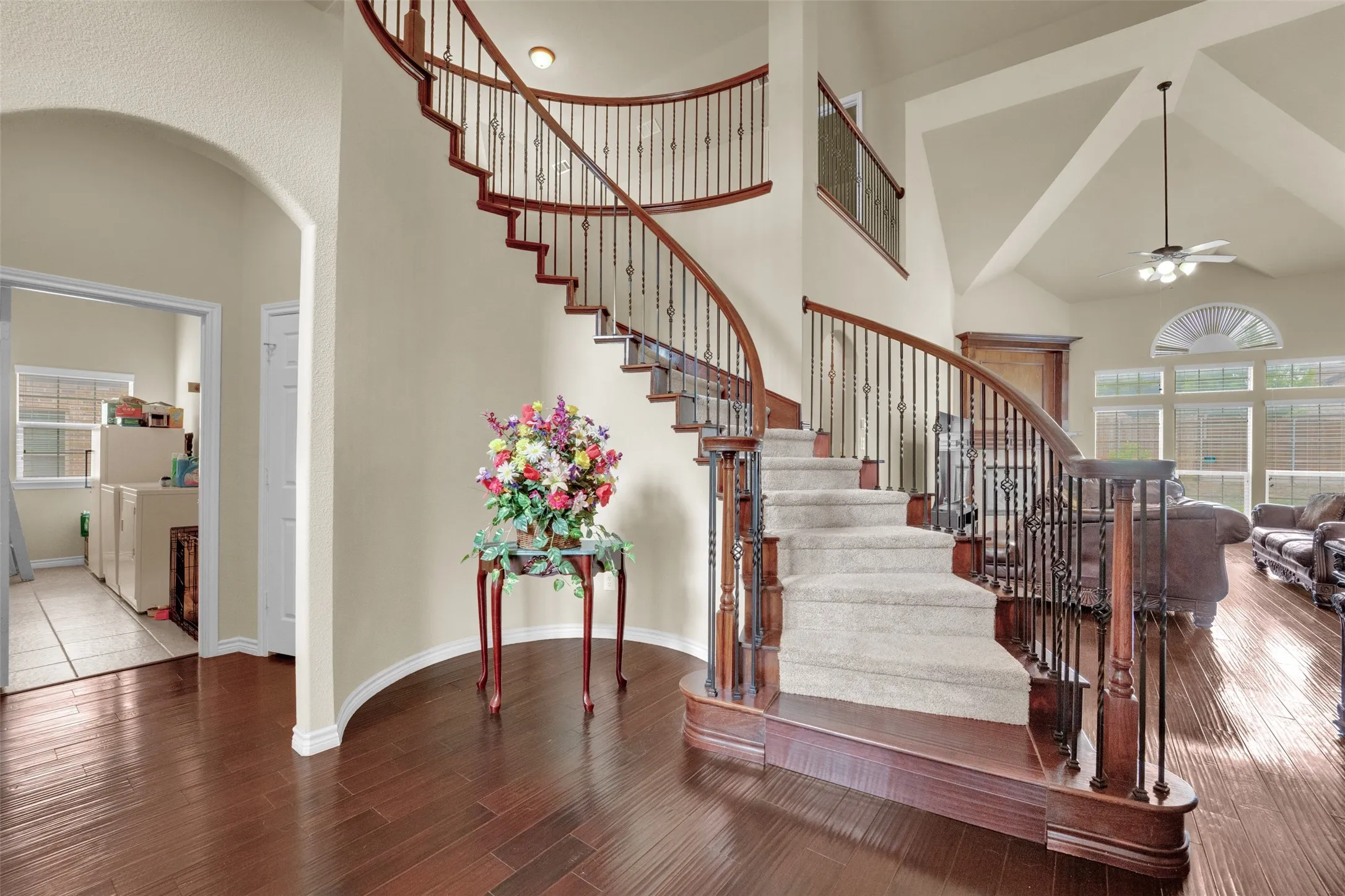 Grand curved staircase featuring dark wood handrails and wrought iron balusters