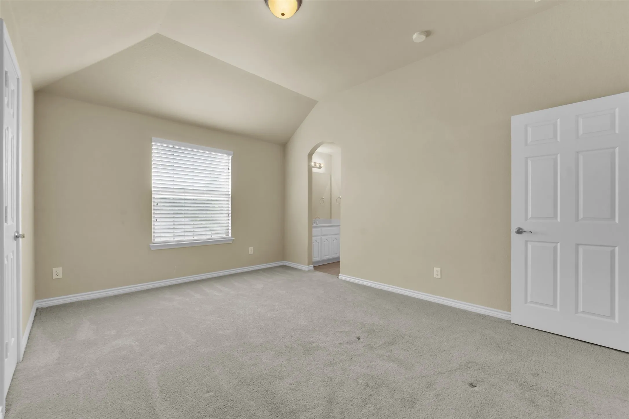 Spacious room with vaulted ceilings and neutral-toned carpeting