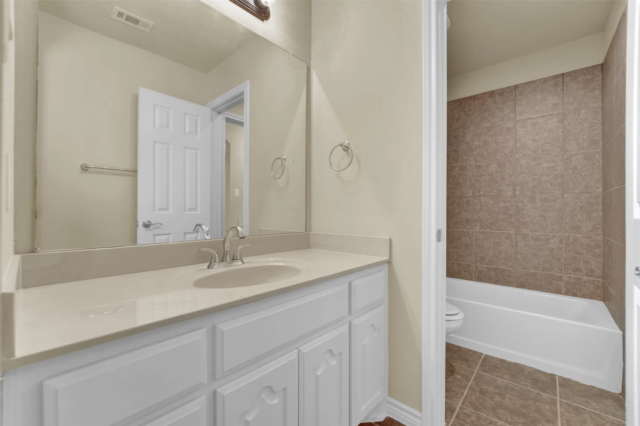 Bathroom vanity with a light-toned countertop, undermount sink, and brushed nickel faucet