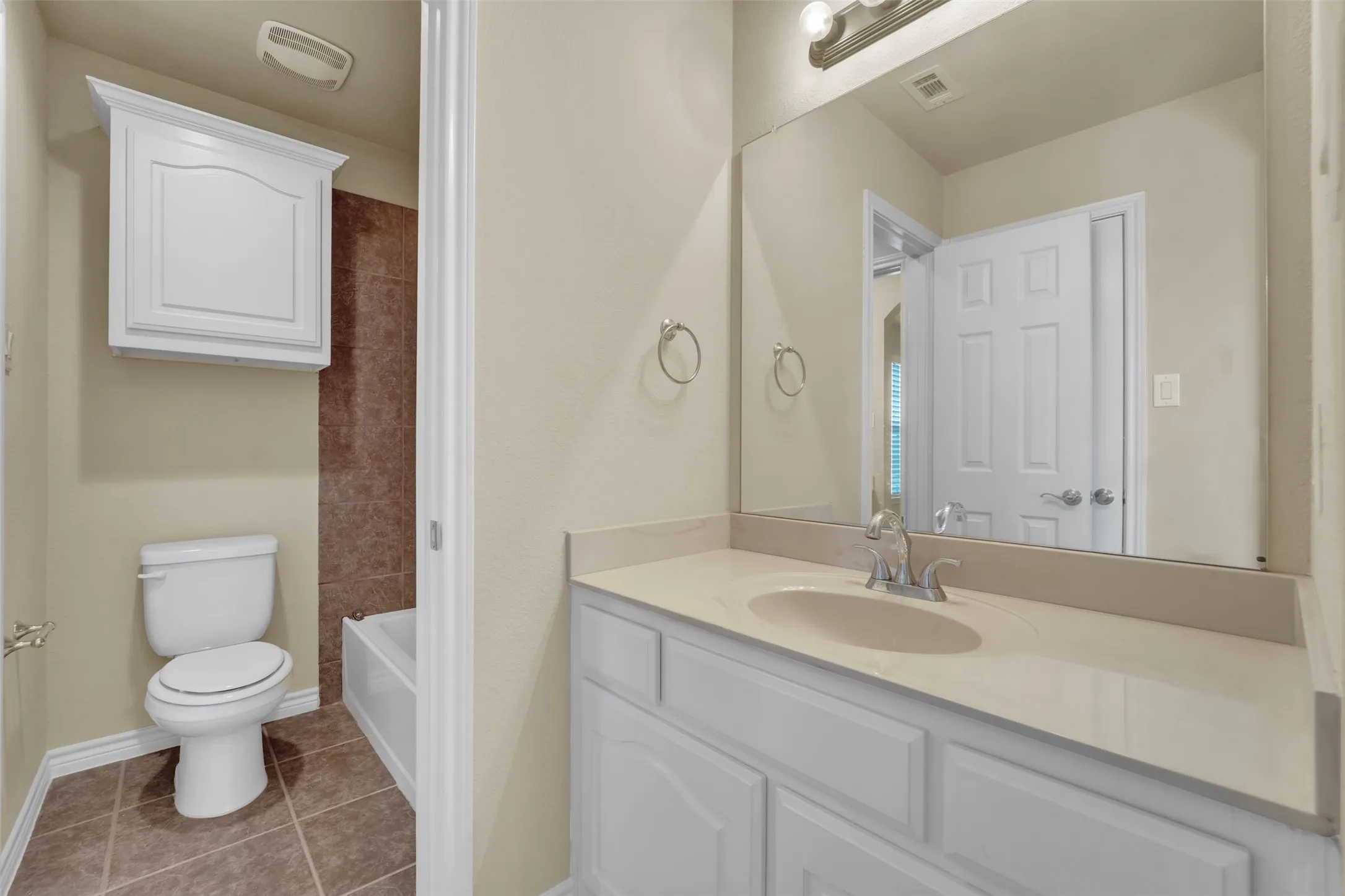 Bathroom featuring a white vanity with an integrated sink, polished chrome faucet, and a large wall-mounted mirror