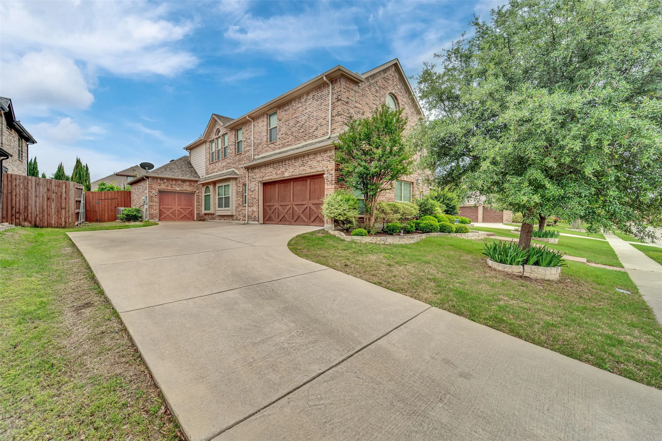 Brick facade residence featuring a multi-car driveway, arched windows, and decorative garage doors
