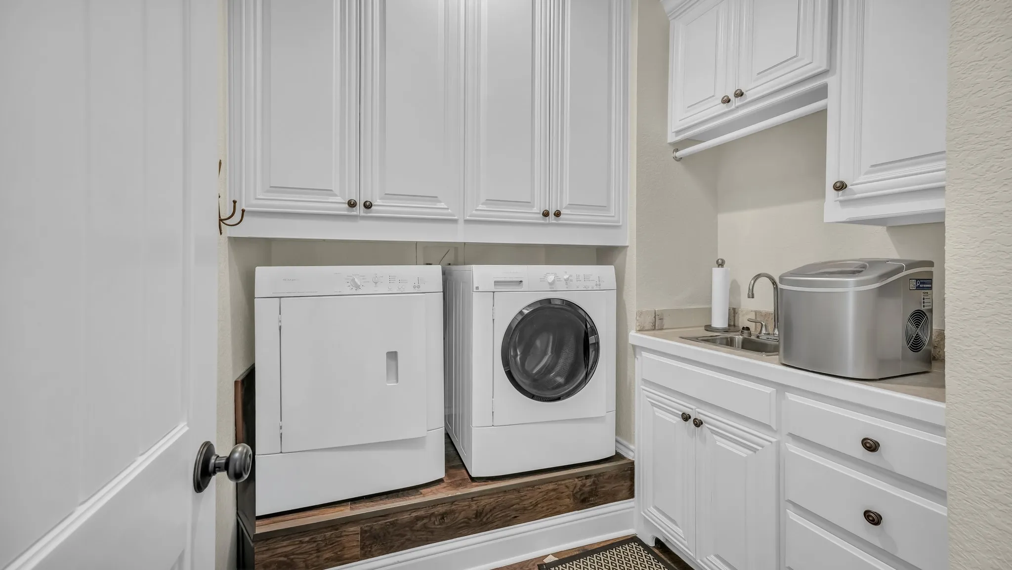 Dedicated laundry room on the primary floor has washer and dryer, sink, and plenty of storage space.