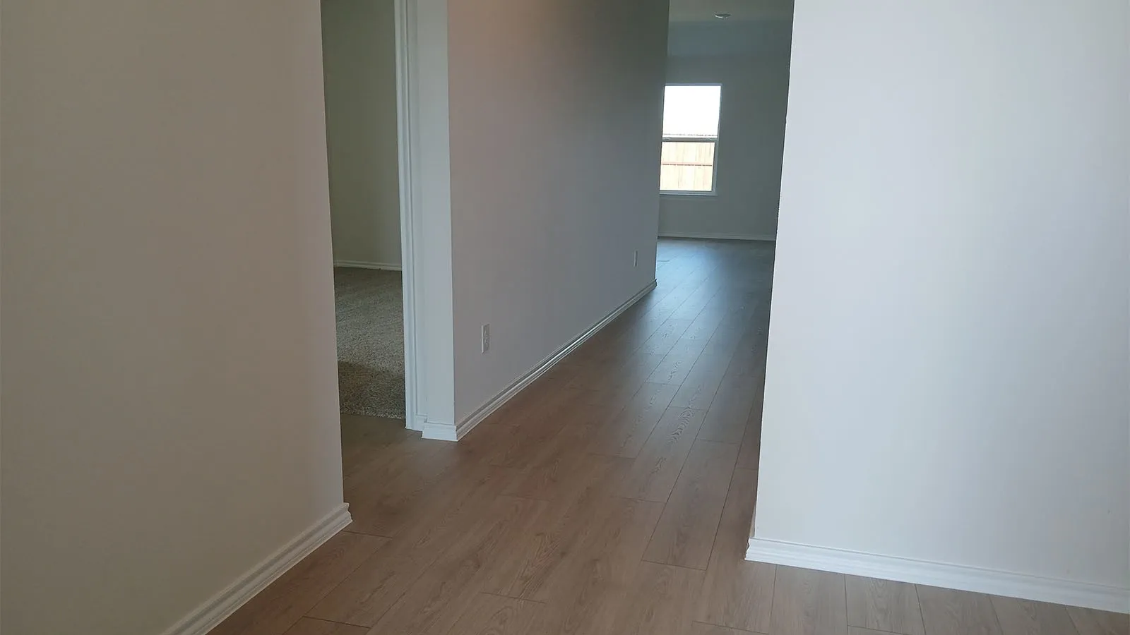 Wood-finish flooring throughout, bright interior with white walls, and a window providing natural light