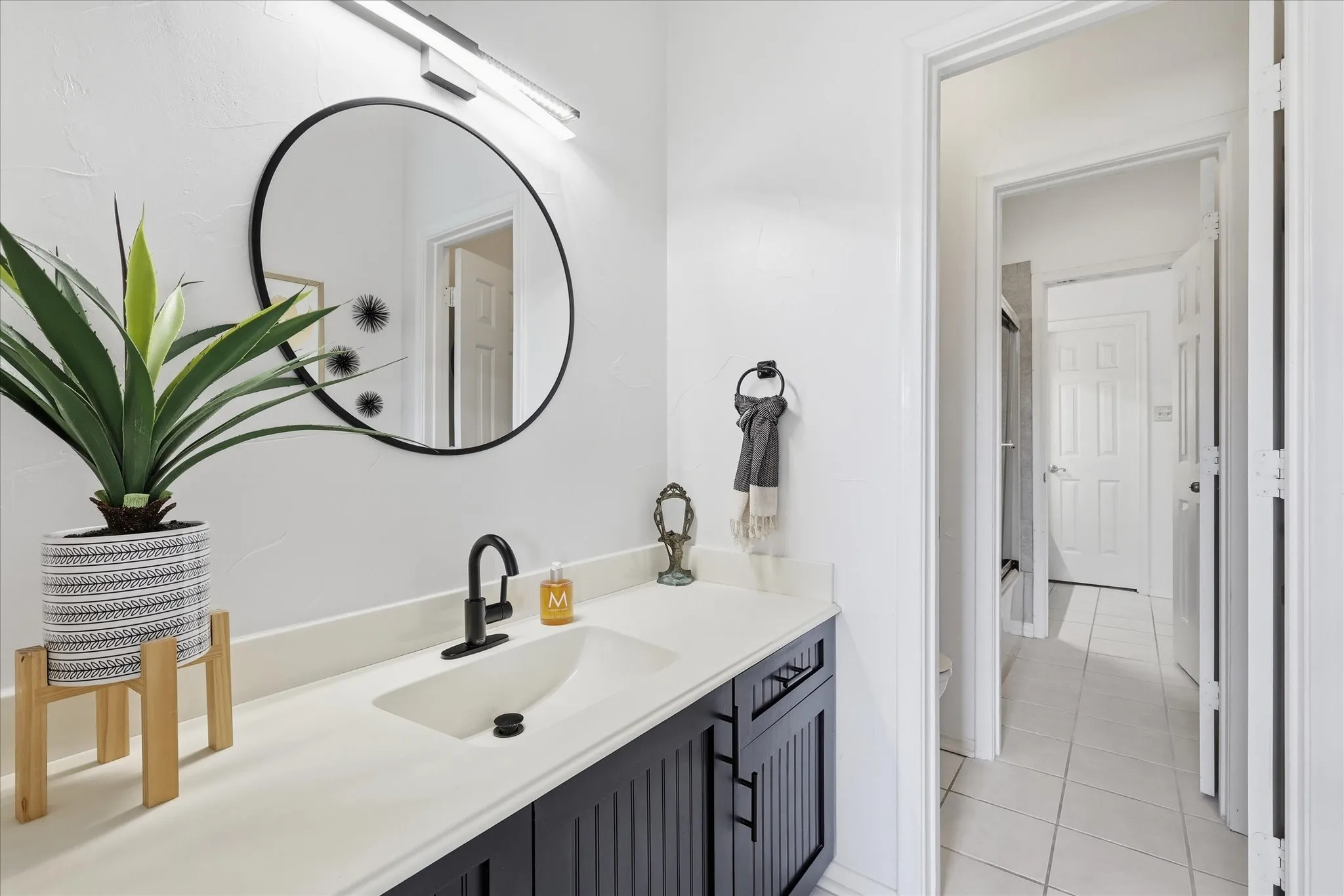 Bathroom vanity featuring a light-toned countertop, integrated sink, and dark-finished cabinetry with vertical detailing