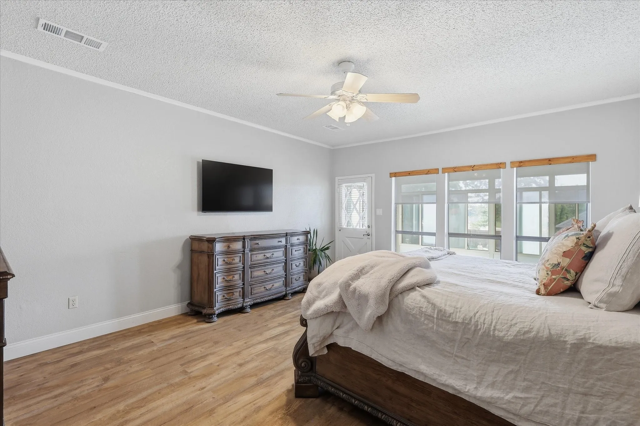 Ample primary bedroom. Daylight streams through multiple windows and a half-lite door that leads to the temperature controlled sunroom.
