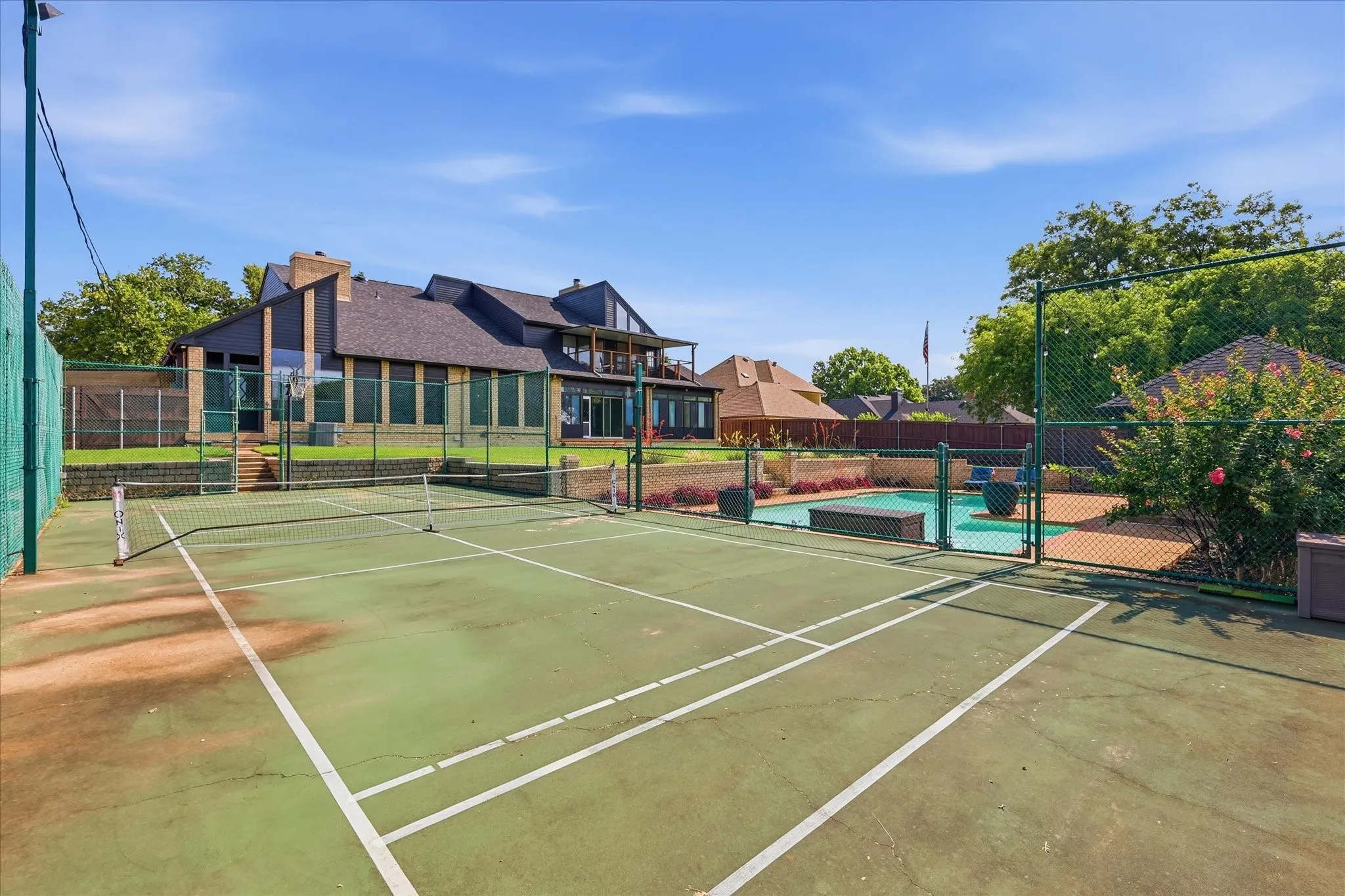 Private sports court with perimeter fencing, adjoining the swimming pool, and an expansive exterior