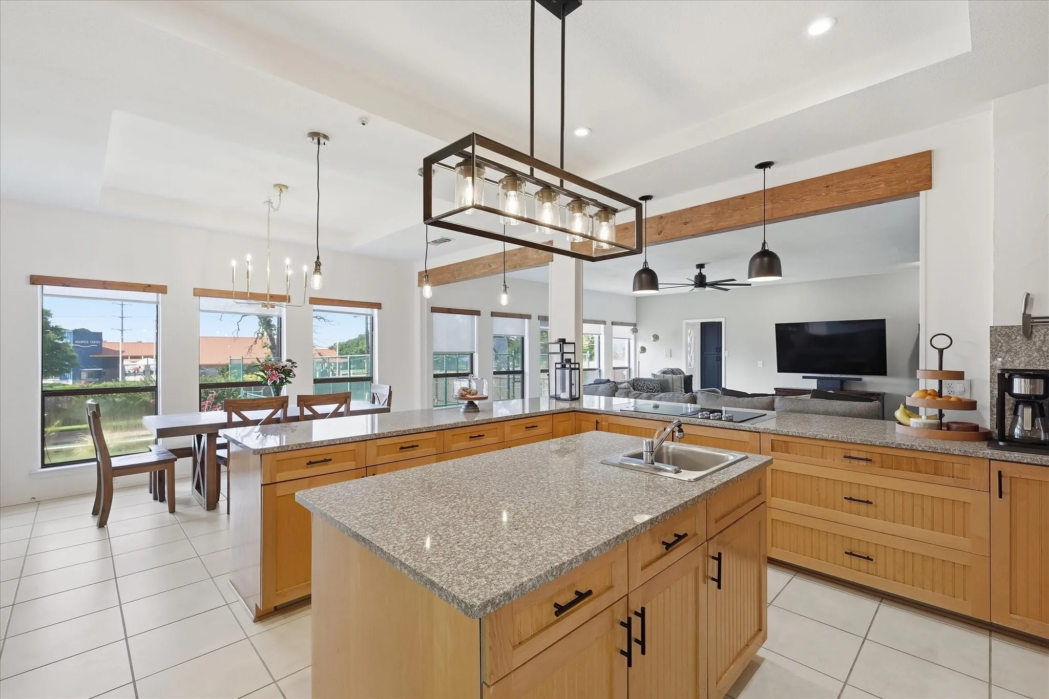 Large kitchen with two sinks, ample storage and counter space, electric cooktop with down-draft vent, under-cabinet lighting and modern light fixtures.
