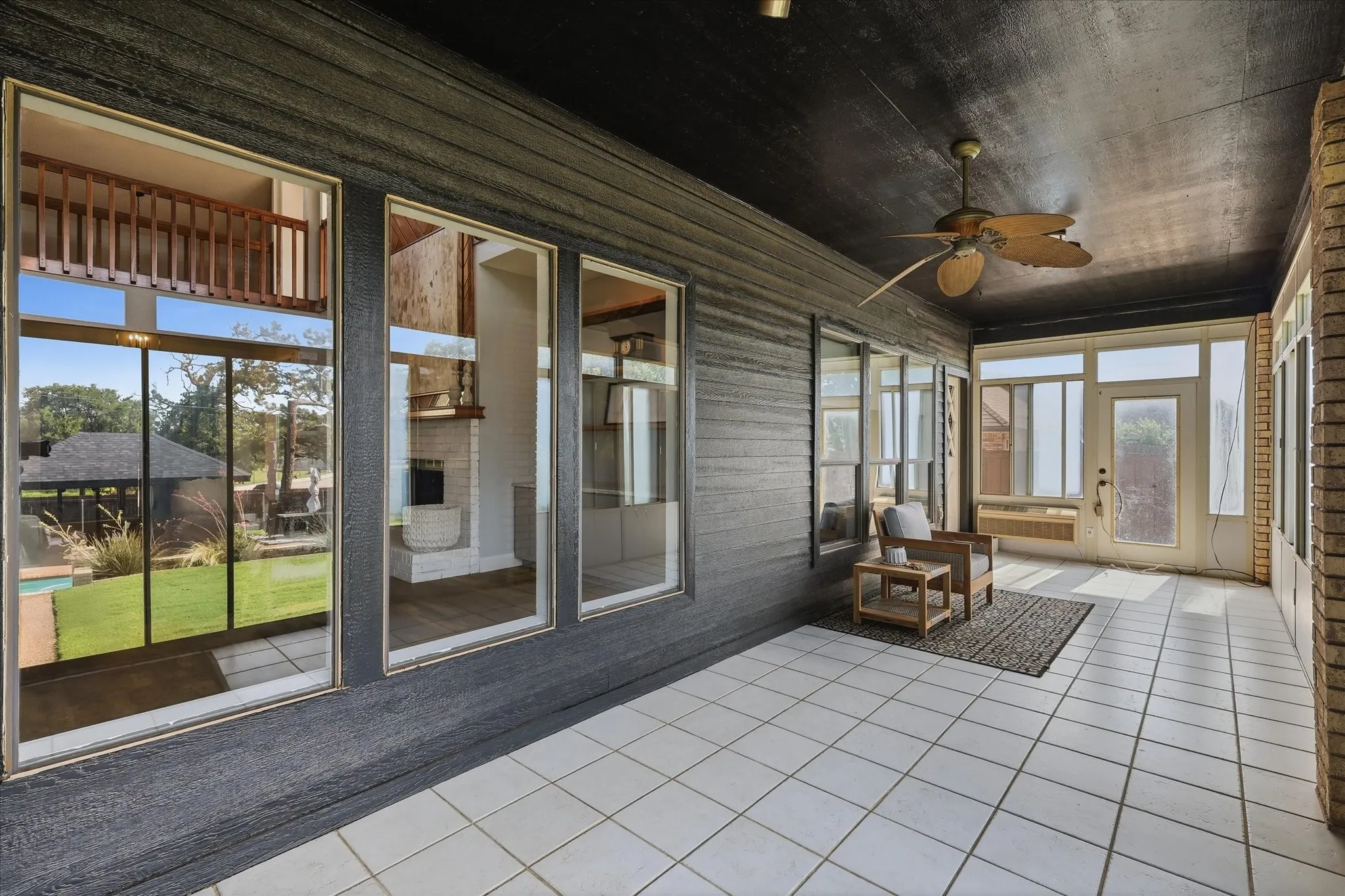 Covered patio featuring a tiled floor, wood-paneled walls, and a ceiling fan