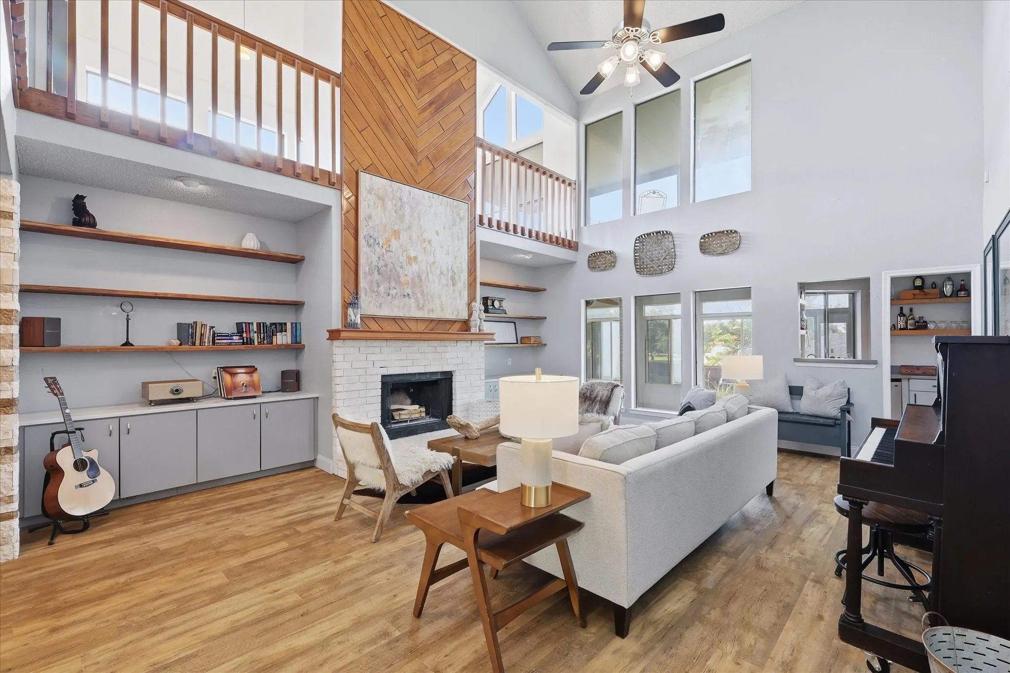 Large living room with open shelving, stone countertops, storage and a tall accent wall with wood-burning fireplace. 6 large windows flood the room with light and access to the butlers pantry keeps entertaining​​‌​​​​‌​​‌‌​‌‌​​​‌‌​‌​‌​‌​​​‌​​ easy.