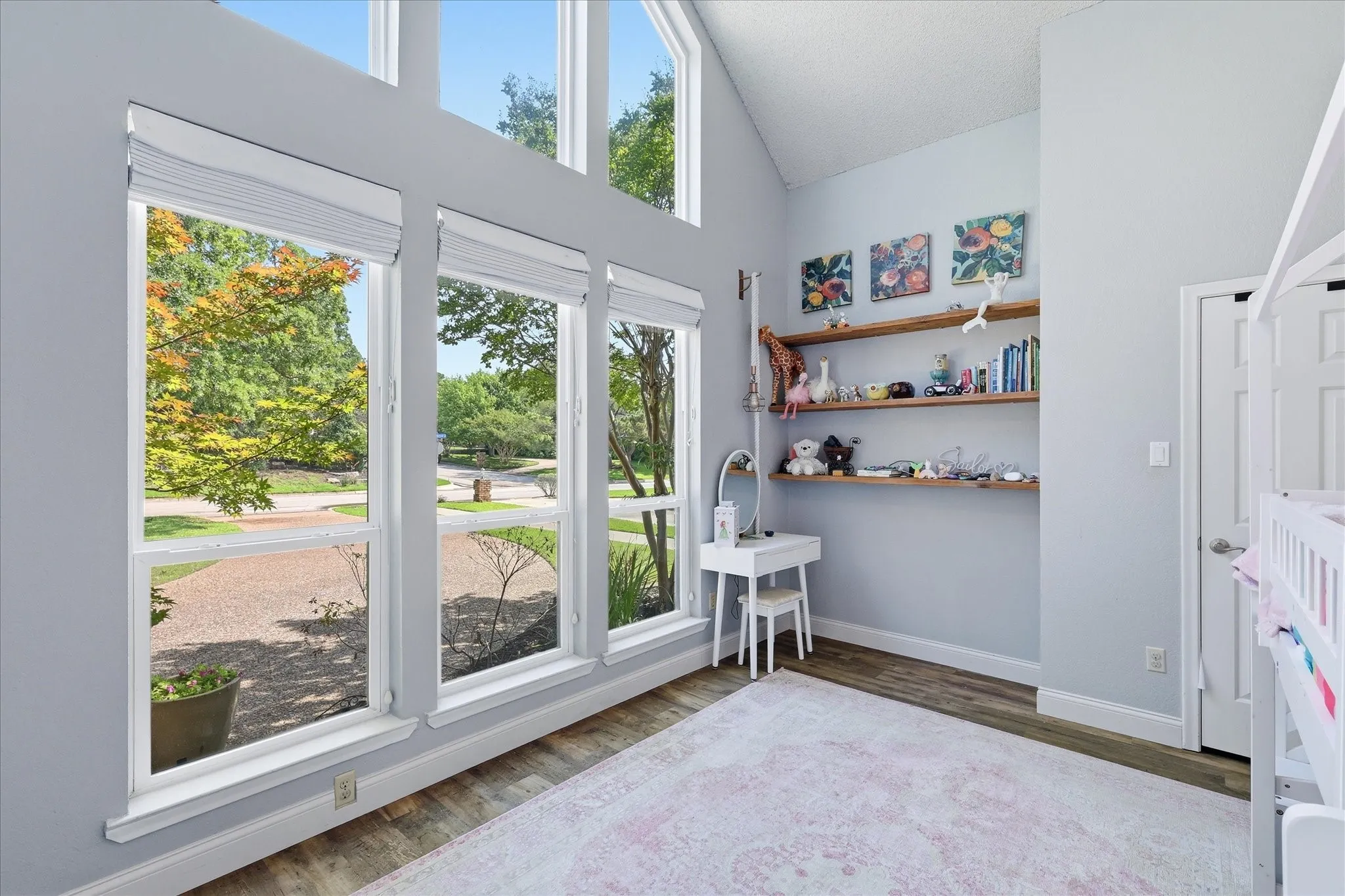 Secondary bedroom on first floor featuring lots of windows, high-angled ceilings and built in shelves.
