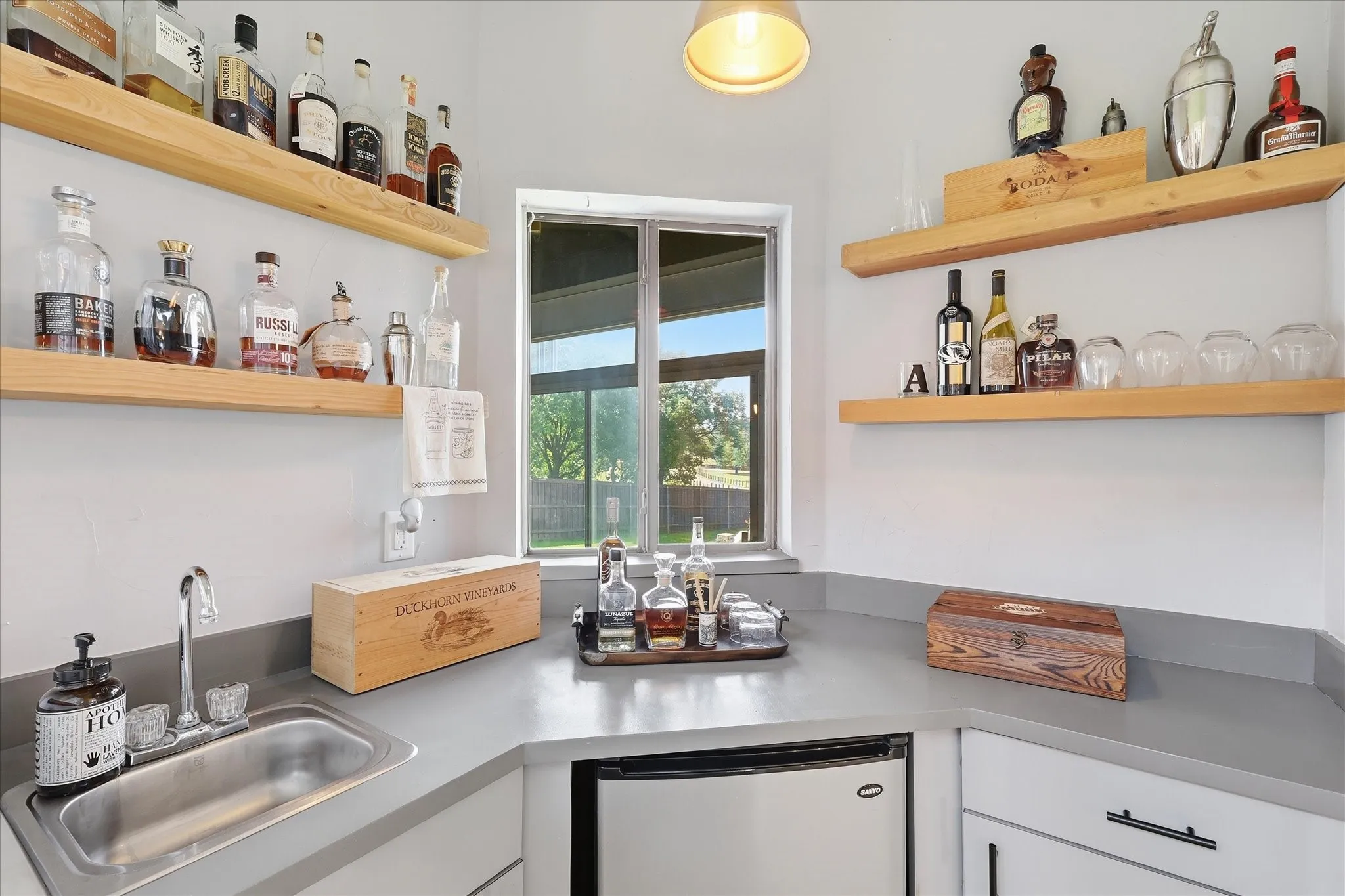 Butlers pantry with mini-fridge, sink and open shelving. Connects kitchen to entry living room.