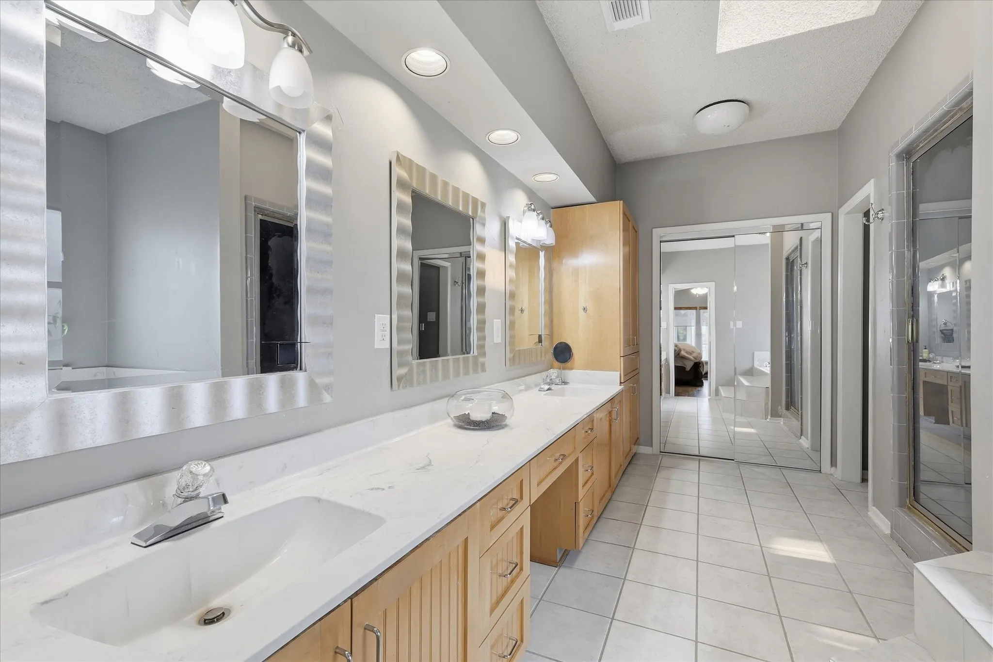 Large primary bathroom with double vanity, walk-in closet with mirrored sliding doors, water closet, separate shower and oversized bathtub.