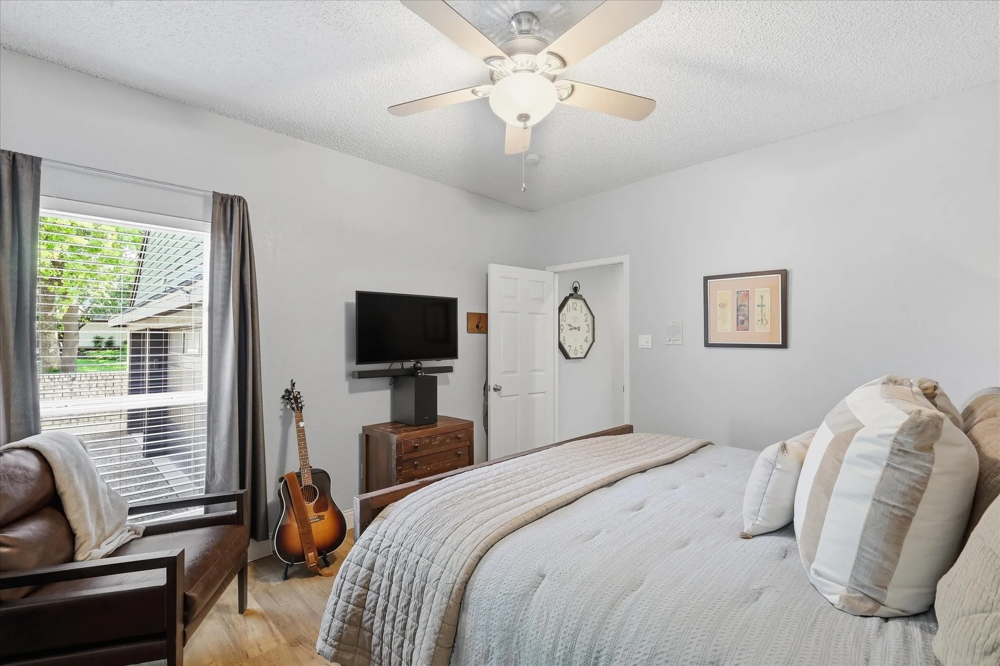 Downstairs secondary bedroom featuring ceiling fan, window with blinds, ensuite and proximity to kitchen