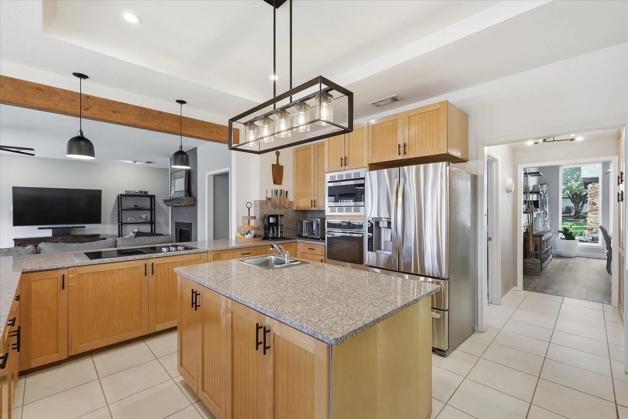 Large kitchen with two sinks, ample storage and counter space, electric cooktop with down-draft vent, under-cabinet lighting and modern light fixtures.