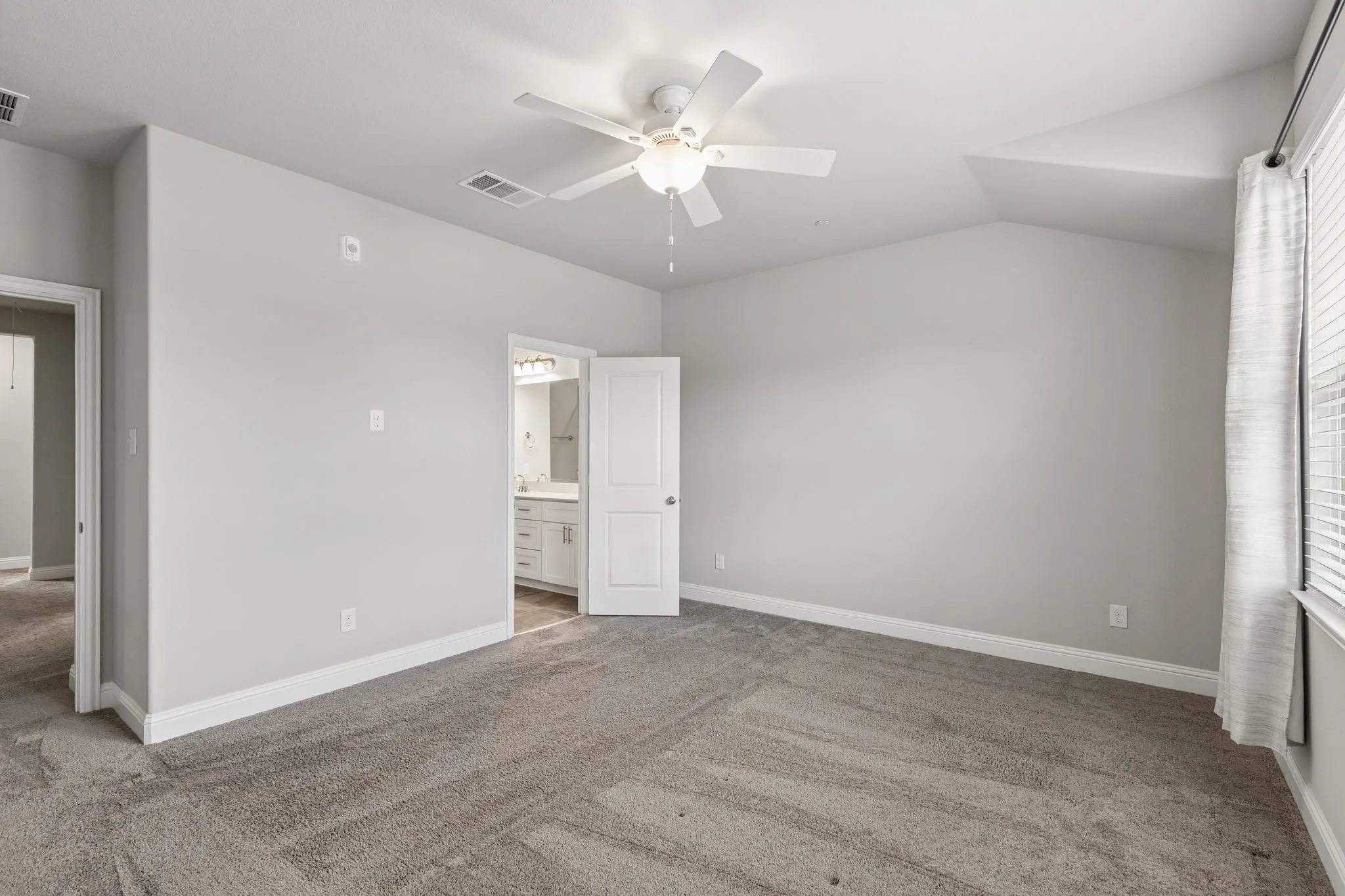 Carpeted room featuring a vaulted ceiling with a ceiling fan, and neutral wall paint