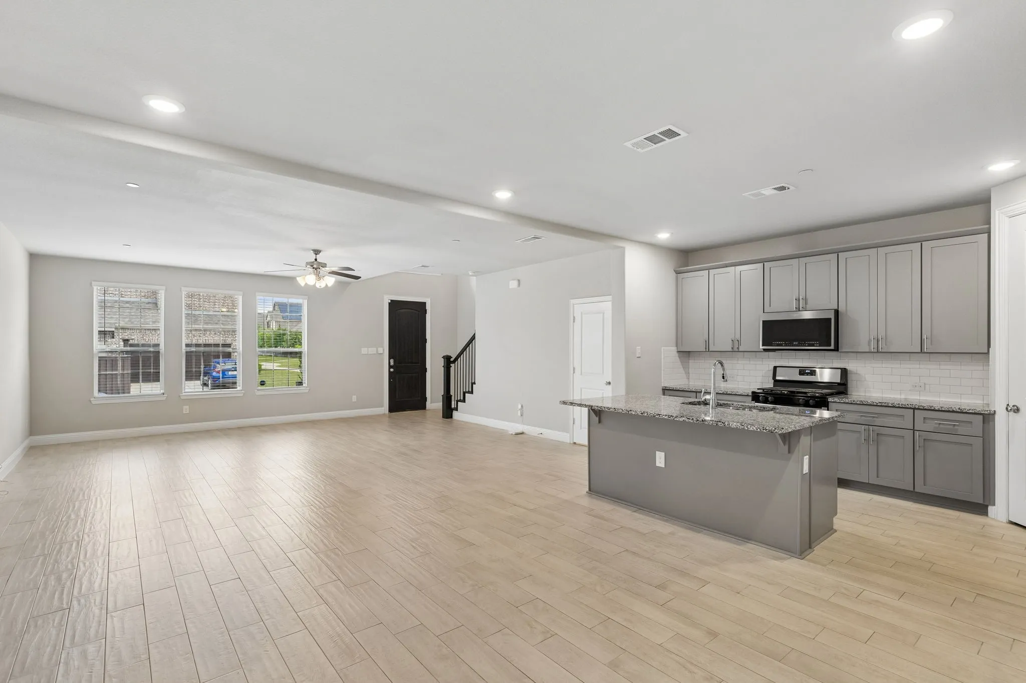 Open-concept living area featuring light wood-finish flooring, recessed lighting, and a contemporary ceiling fan