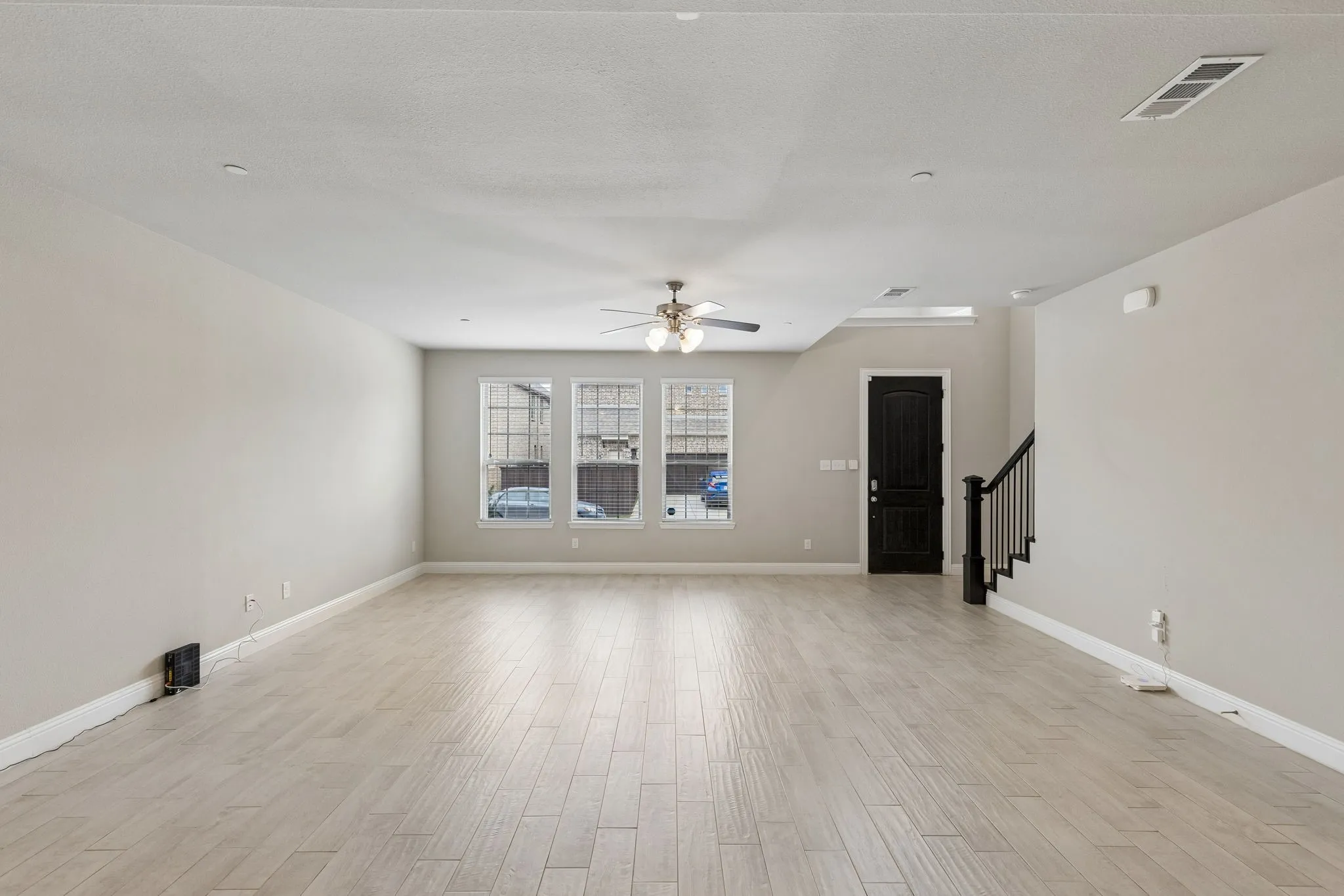 Spacious room featuring wood-finish flooring, light neutral wall tones, and recessed lighting