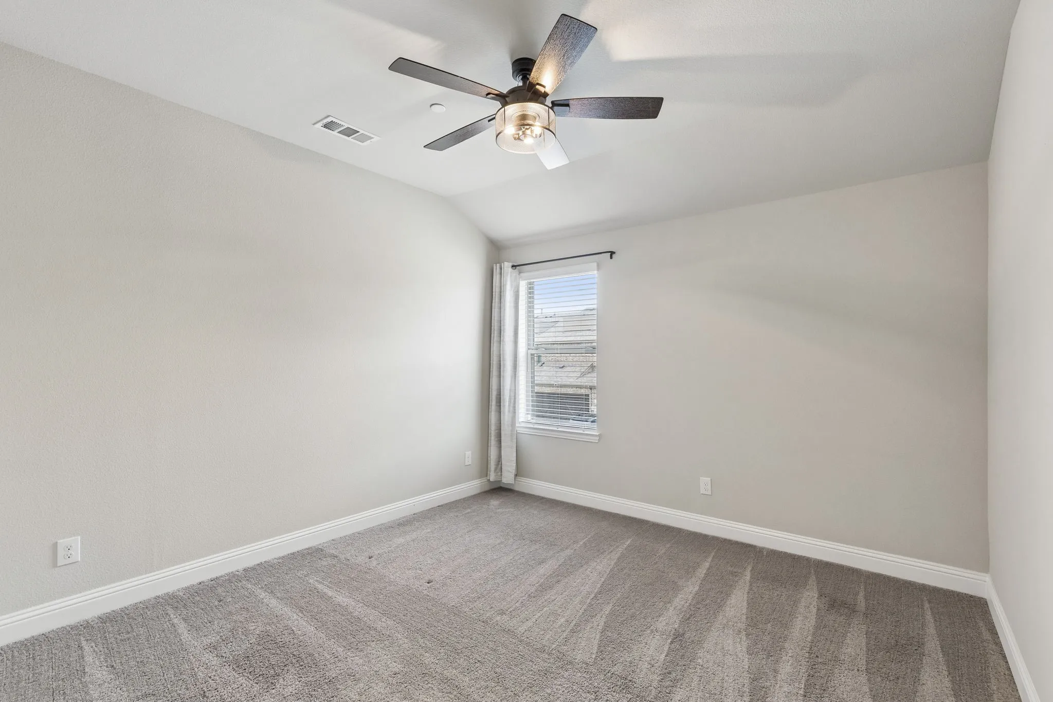 Vaulted ceiling bedroom with a ceiling fan light fixture, light gray carpet, white baseboards, and a window with blinds