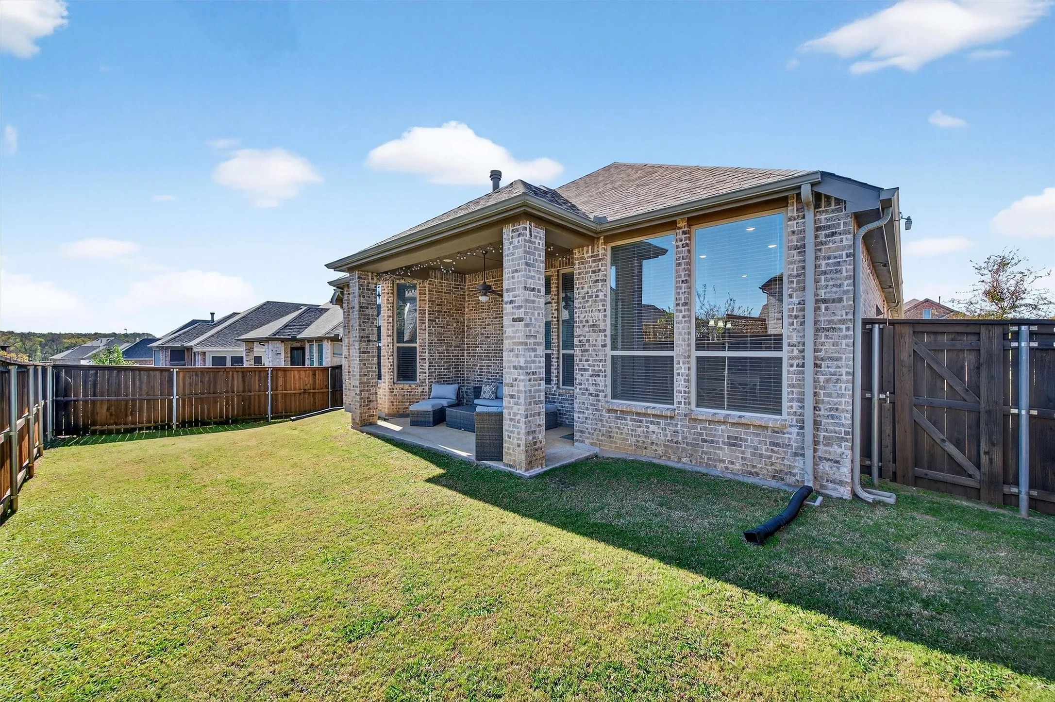 Rear view of property with a fenced backyard, brick siding, a patio area, and a gate