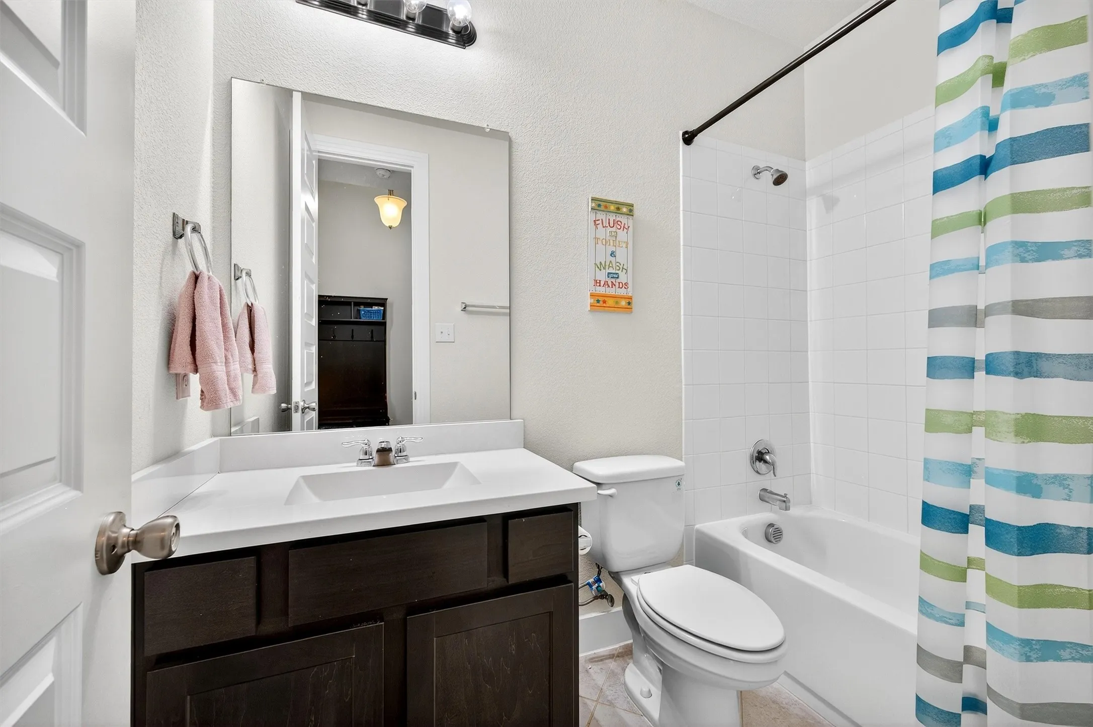 Full bathroom featuring shower / bath combo with shower curtain, vanity, and a textured wall
