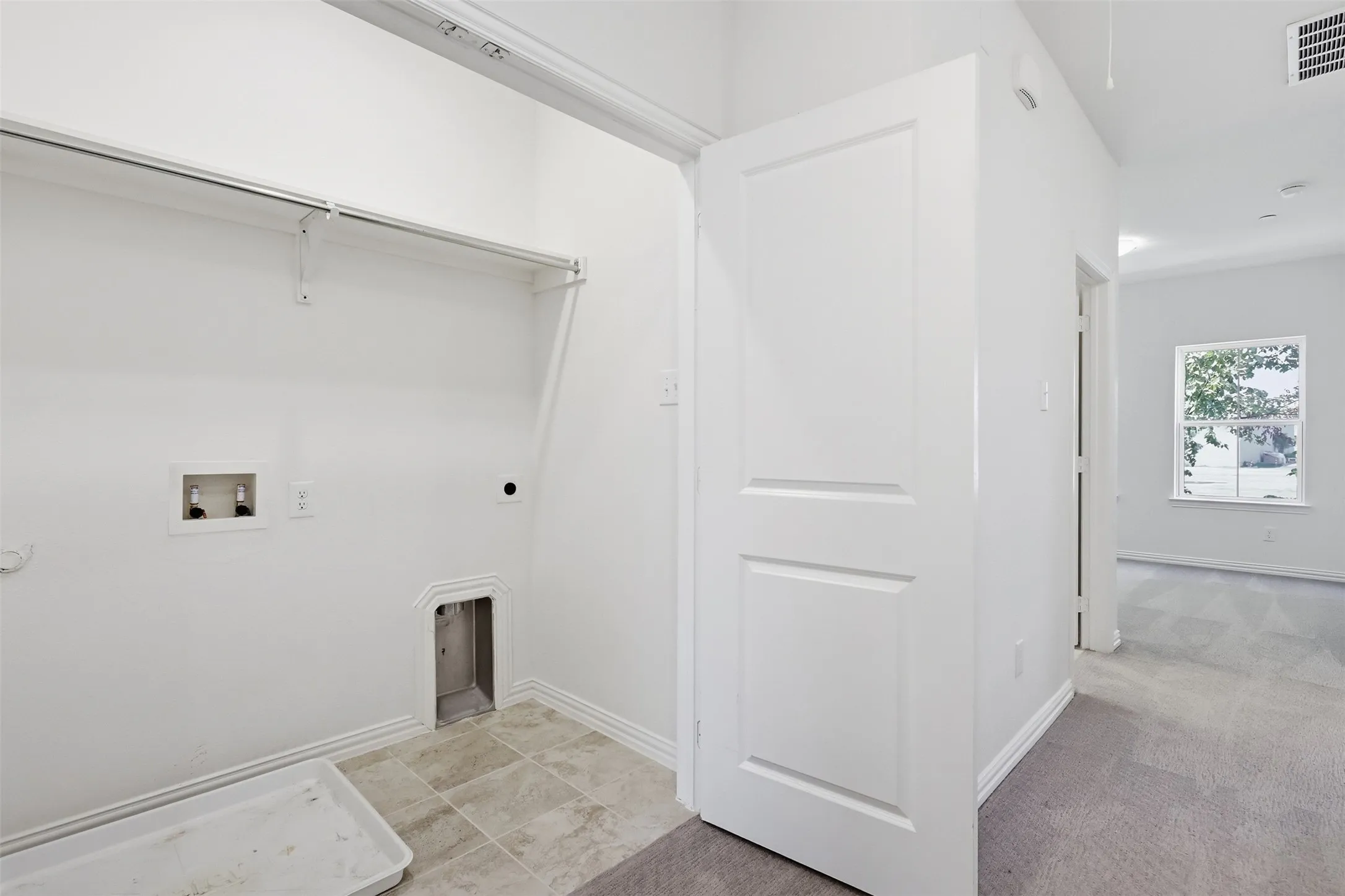 Utility area upstairs featuring tile flooring, a clothes hanging rod, and appliance hookups