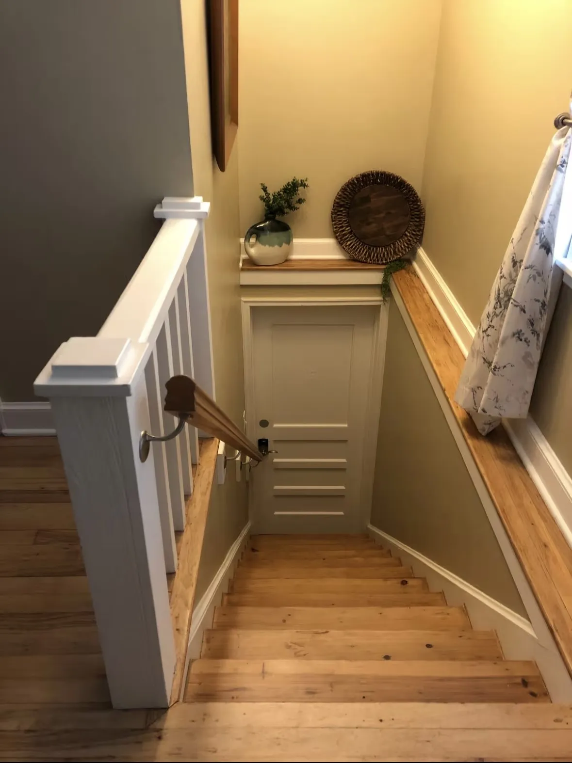 Hardwood stair treads featuring a white painted balustrade and a matching handrail, leading up to the third bedroom above the garage storage area. Very private.