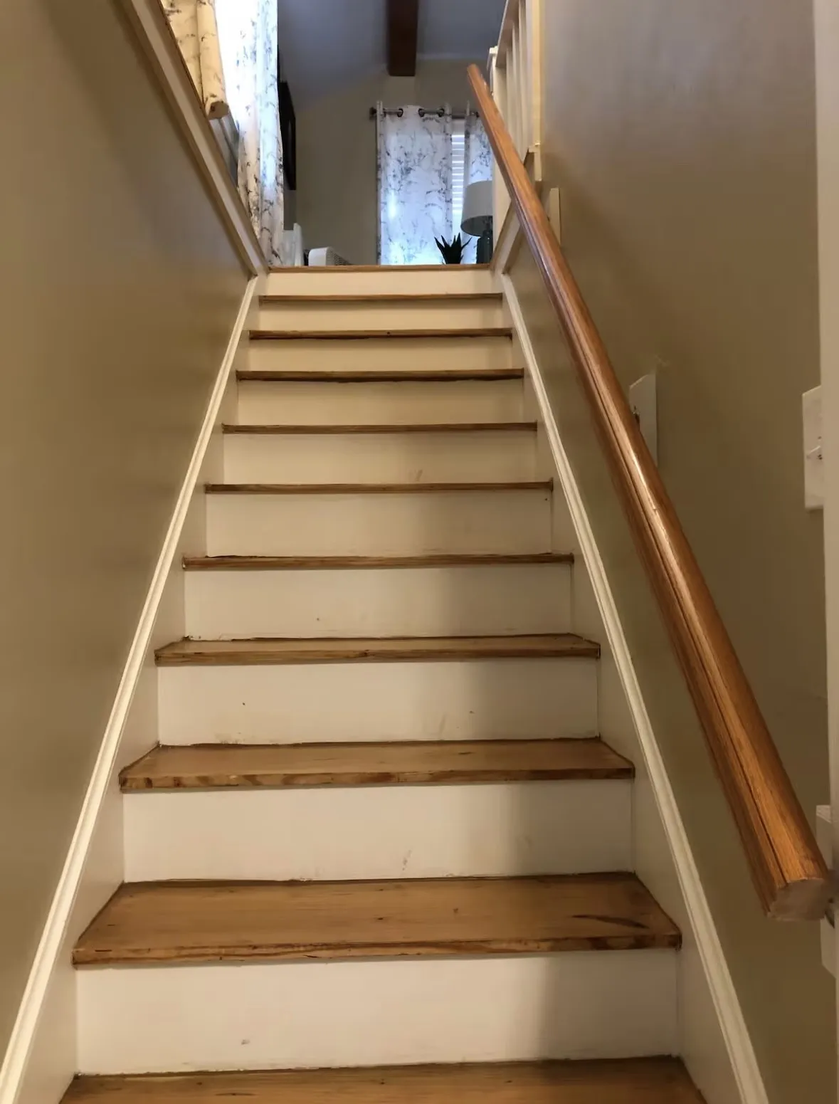 Staircase featuring wood treads, white risers, and a natural wood handrail