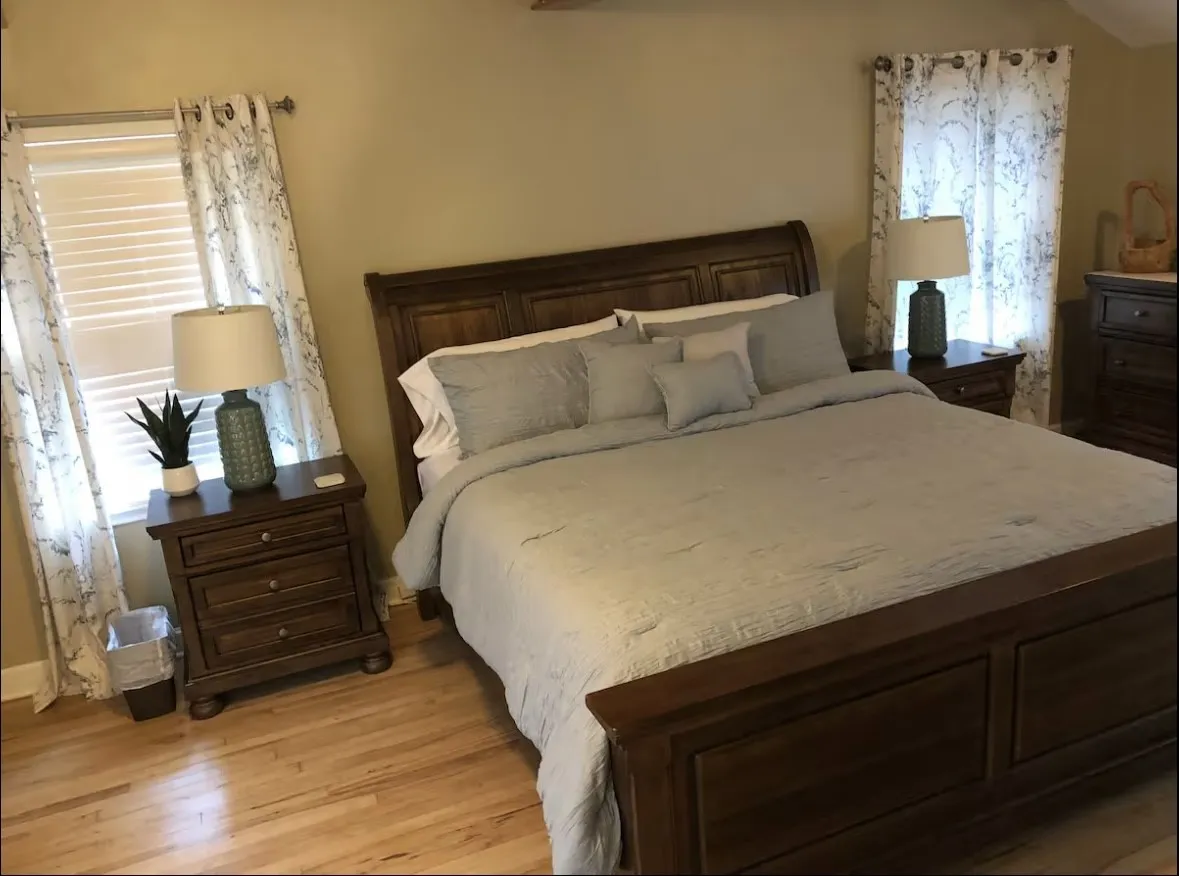 Bedroom with light wood-finish flooring, light-toned walls, and two windows