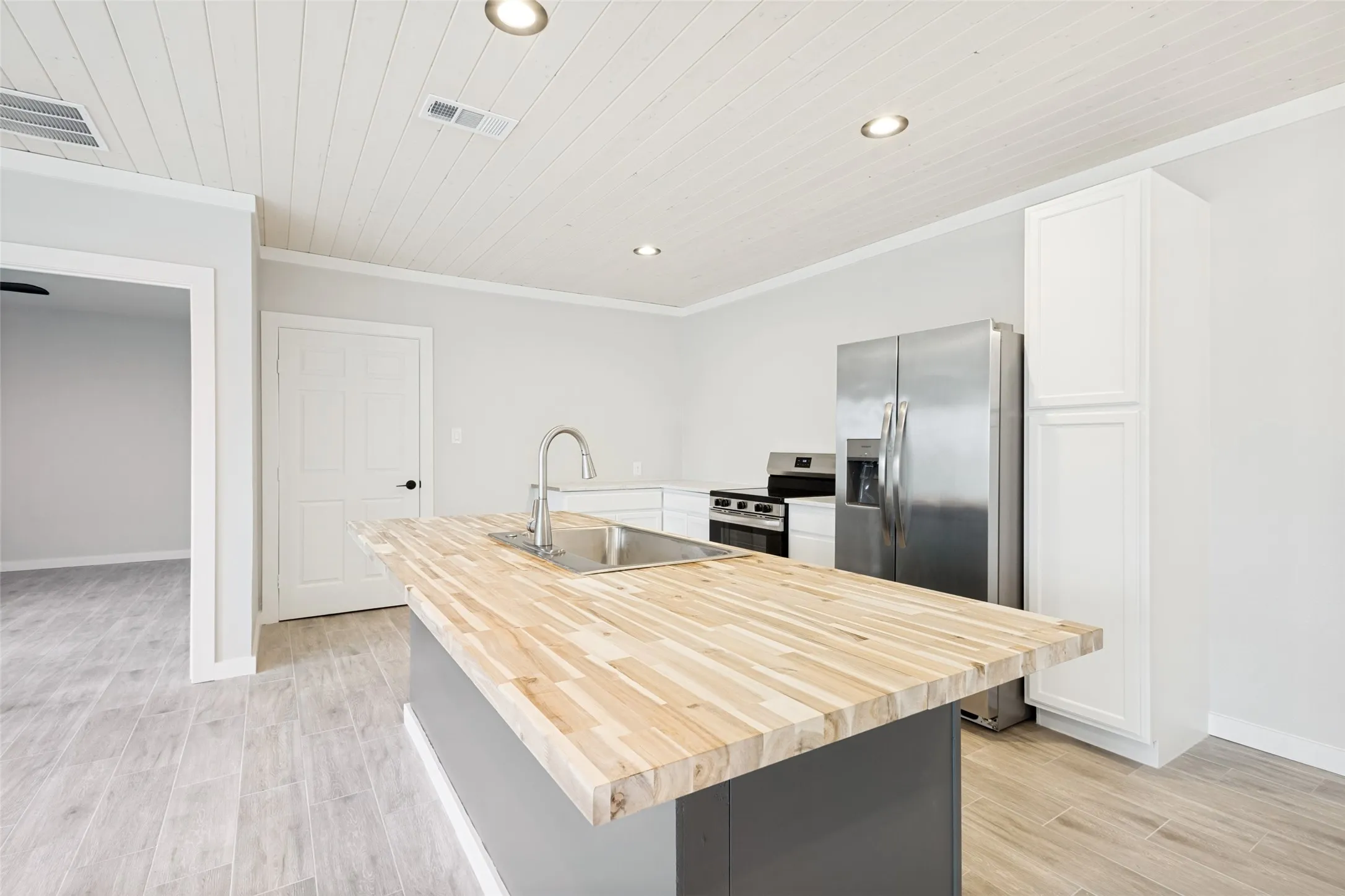 Guest house -Kitchen featuring a butcher block island with an integrated sink and gooseneck faucet